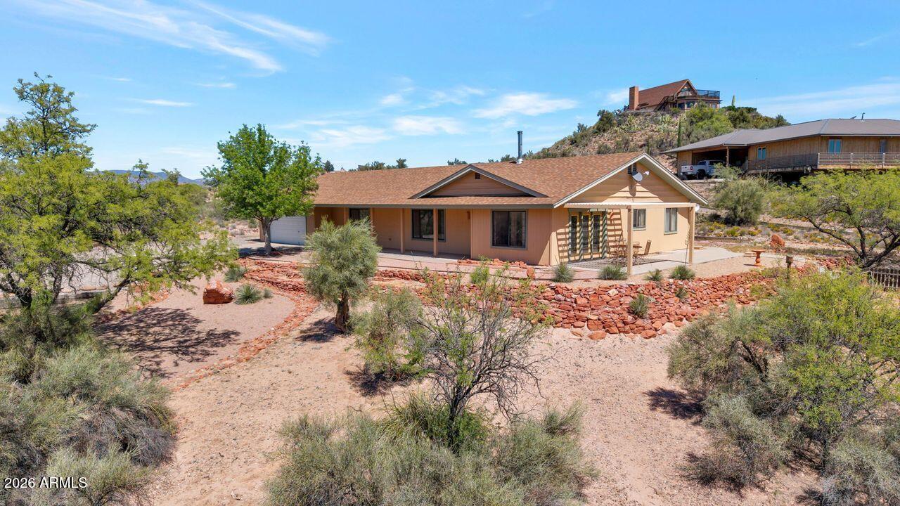This home and its location truly have so much to offer! Experience the charm of this meticulously cared for home where tranquility and breathtaking views of Mingus Mountain create the perfect backdrop for everyday living.
Offering 2,268 square feet, this thoughtfully designed home features three spacious bedrooms and two bathrooms.  The inviting living room showcases a cozy wood-burning stove and panoramic mountain views, complemented by attractive wood-grain laminate flooring.  Authentic Saltillo tile flows throughout most of the home, adding warmth and character, while the carpeted bedrooms provide a comfortable retreat.
Storage is abundant and seamlessly integrated throughout the home, making organization effortless. For those who enjoy creative pursuits or need a dedicated workspace, the heated and cooled workshop/artist studio offers year-round flexibility for hobbies or projects.
Set on an acre +, the property provides exceptional privacy, along with a fenced garden area and a convenient storage shed--ideal for gardening enthusiasts.
Additional highlights include a private well, an oversized garage with a workbench and cabinetry, and ample space for RV parking. The property is also horse-friendly, making it perfect for those seeking room to enjoy outdoor and recreational activities.
Enjoy peaceful living while being just minutes from Old Town Cottonwood, where you'll find restaurants, shopping, hiking, canoeing, and more.
AI-generated photos are included to help you envision the property's potential with only minor upgrades and changes to primarily the landscaping.