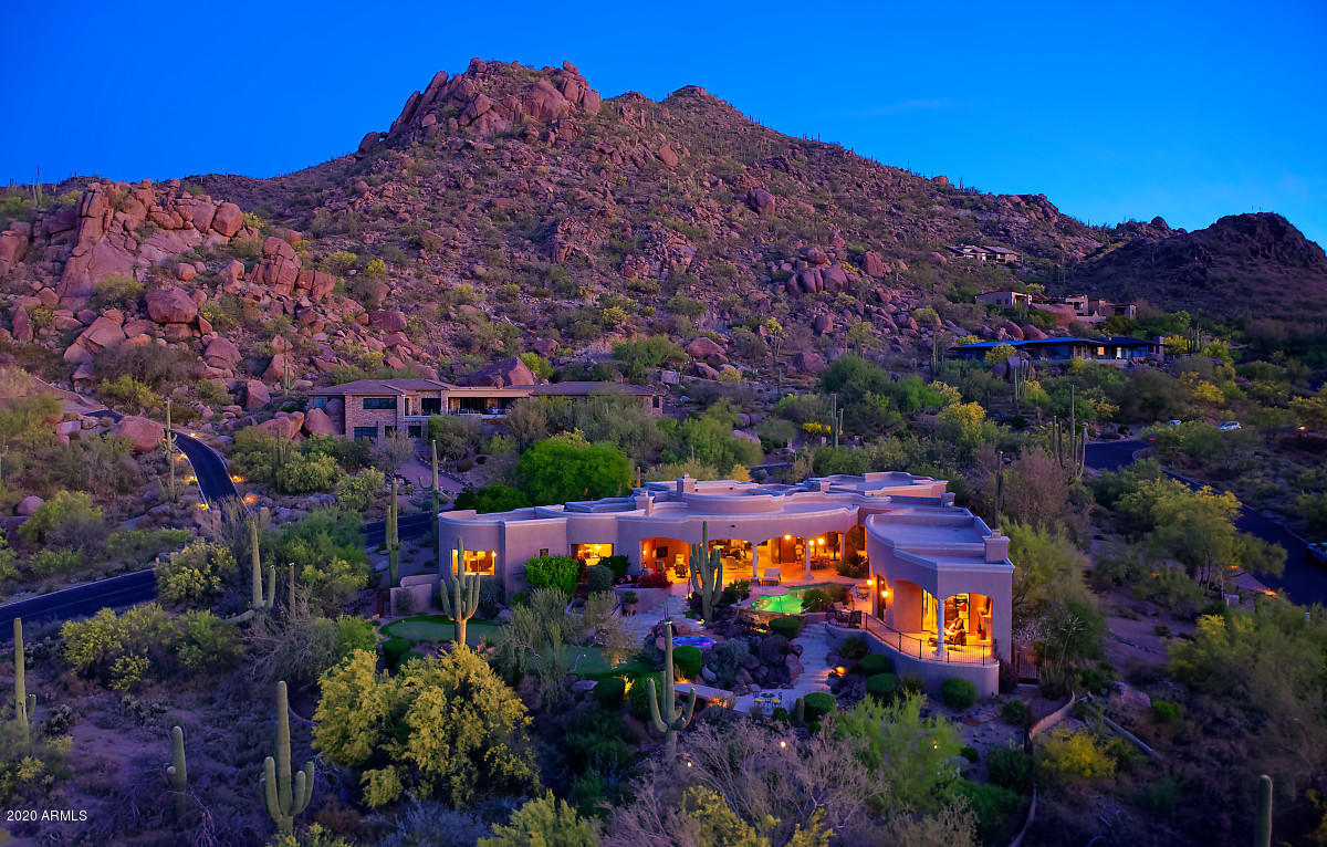 Discover this enchanting and timeless  Mediterranean Hacienda set in a lush 2-acre desert oasis and nestled among the dramatic boulder croppings and the gentle sloping hillside of Black Mountain. This sophisticated 4 bedroom 4.5 bath custom home offers unrivaled city and boulder pile views with architecture that blurs the boundaries between inside and out. Inviting living spaces extend onto outdoor terraces for open-air dining and merging into a world class resort backyard featured in Phoenix Home & Garden magazine.  Inside you'll find high end finishes with extensive use of Cantera stone and natural materials. A stunning chef's kitchen includes a butler's pantry, an oversized granite center island and stainless steel appliances. The secluded master retreat offers large dressing area with washer/dryer and luxurious, spa-like bathroom. The split-floor plan offers a private 2-bedroom ensuite guest wing within the main residence and a perfectly situated separate 2-room guest casita w/ full kitchen sits across the courtyard's lush gardens with its own private patio and sweeping views of  The Boulder resort golf course. Luxury amenities include a firepit with built-in banco seating  alongside a negative edge pool that terraces down alongside steps to the spa and putting green. A fabulous open air ramada with outdoor kitchen has an oversized stone island with built-in fire feature, and two separate open air-living rooms take outdoor living to a new level. Find serenity and seclusion in this romantic hacienda estate with the convenience of nearby shopping, dining, and world-class golf courses just minutes away.