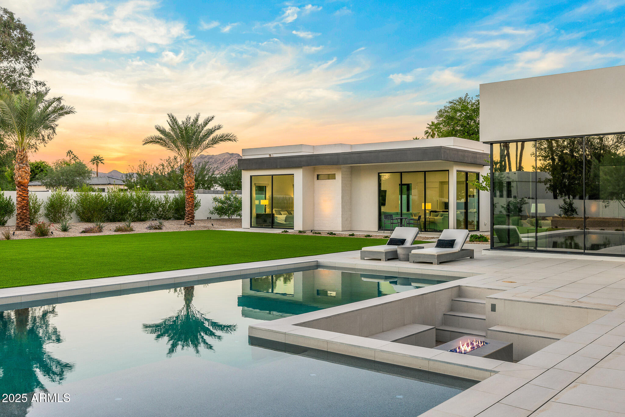 With its modern architecture, striking curb appeal, and sweeping Camelback Mtn views, this gated home with full guest house is truly the one you've been waiting for. This private estate offers 5 bedrooms, 7 bathrooms, a 6+ car garage, dedicated office, and a home gym, all wrapped in chic design and serene living spaces. The primary retreat is an inviting sanctuary, featuring telescoping doors, a cozy fireplace, and a convenient coffee station. The luxurious primary bath includes an impressive walk-in closet with double islands, a washer and dryer, dual vanities with a makeup area, a soaking tub, a walk-in shower, and even a privately enclosed outdoor shower. The guest wing includes its own secondary family room, a theater with projection screen, and three en-suite guest bedrooms. The guest house lives as its own house. It has a large bedroom with a washer/dryer in the walk in closet, double vanity bath, a living room and an open kitchen that includes a full-size refrigerator and oven. Entertaining is effortless in the spectacular chef's kitchen, complete with two oversized islands, Wolf/SubZero appliances, custom cabinetry, and a coffee station. Enjoy meals in the spacious formal dining room with a floor-to-ceiling wine display, or dine outdoors under the expansive covered patio while taking in breathtaking Arizona sunsets. Spend your weekends exactly as you choose: swimming in the heated pool, relaxing by the sunken fire pit, or gathering around the outdoor kitchen. Whatever your plans, this exceptional home checks every box.