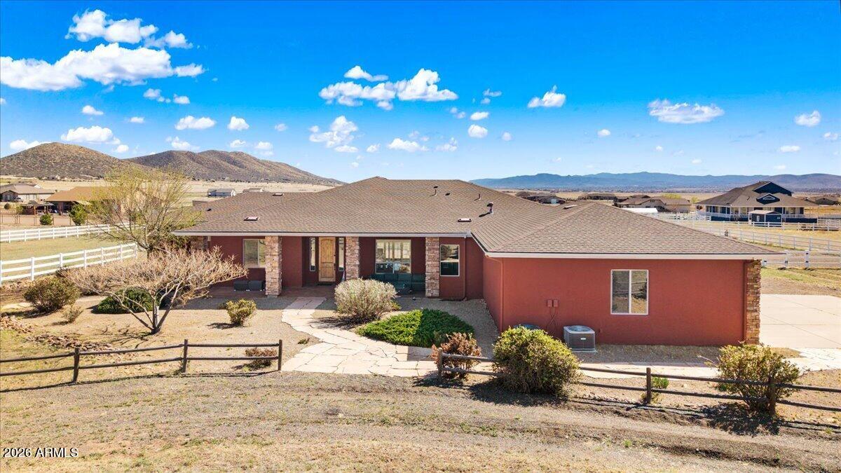 Welcome to your own slice of country living, where space, views, and freedom come together. Set on 2 usable acres in the sought-after Prescott Prairie equestrian community, this property offers private access to horse and OHV trails along with wide-open 360° views that truly set it apart. Inside, the home is designed for both comfort and connection. The spacious primary suite opens directly to the back patio, perfect for enjoying quiet mornings or evening sunsets. You'll appreciate the thoughtfully designed walk-in closet with custom organization and a spa-like ensuite featuring a jetted tub and separate walk-in shower. The heart of the home is the open living area, where the kitchen and living room flow seamlessly together, creating an ideal space for entertaining. A cozy stone gas fireplace anchors the room, while sliding doors lead provide tons of natural light and lead out to an expansive patio complete with a custom 6-foot fire pit, an incredible spot to take in those Arizona sunsets. The kitchen is well-equipped with stainless steel appliances, including a 5-burner gas cooktop, built-in oven and microwave, and a quiet Bosch dishwasher. Granite countertops, a large island with sink, and a spacious pantry make it as functional as it is inviting, all complemented by a dining area with beautiful views. Additional features include a split floor plan for added privacy, two guest bedrooms (one with its own ensuite), and an oversized laundry/mud room off the 3-car garage with ample storage and a utility sink. Hardwood flooring, arched walkways, and upgraded finishes add warmth and character throughout.
