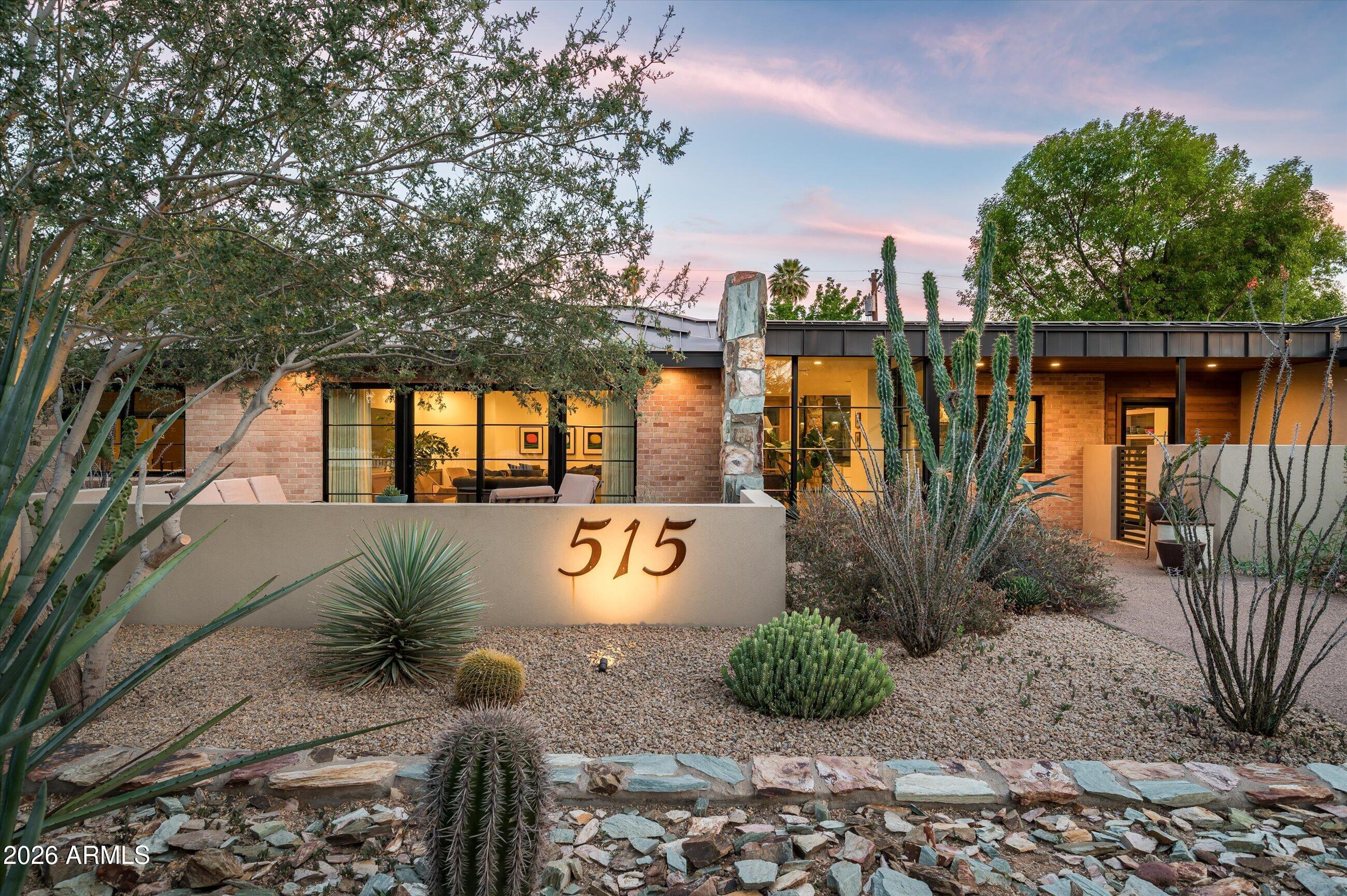 An extraordinary expression of architectural vision and curated design, this reimagined rambling ranch in North Central's coveted ''7's'' seamlessly blends modern refinement with organic desert sensibility. Set behind a lush, water-wise botanical landscape, the approach is nothing short of artful- layered plantings, sculptural stonework, original peach-hued block, and a striking metal roof create a dynamic interplay of texture, tone, and form.

A glass-and-steel entry pavilion introduces the home with a sense of intention and quiet drama, opening to interiors that are both sophisticated and delightfully unexpected. At the heart of the residence, a showpiece kitchen and great room unfold- anchored by vibrant quartzite surfaces, high-gloss custom cabinetry, and herringbone-laid French oak flooring. A fully integrated appliance suite by Wolf and Sub-Zero pairs performance with precision, while curated designer lighting adds a sculptural layer to the space- equally suited for elevated entertaining or intimate daily living.

Spanning approximately 3,650 square feet on an over 15,000 square foot lot, the home is thoughtfully composed with three luxurious en suite bedrooms, a dedicated office, guest powder room, laundry room, and a versatile flex space or gym complete with its own powder room. The floor plan flows effortlessly, balancing openness with purposeful separation- creating a home that lives as beautifully as it presents.

A comprehensive 2019 renovation, led by architect Susanne Rothwell, brings a cohesive architectural language throughout, while the homeowner's expertise in interior and landscape design is evident in every detail. Materials and finishes have been meticulously selected for both quality and artistry, including Heath Ceramics tile, Neff custom cabinetry, quartzite surfaces, Visual Comfort lighting, Kohler fixtures, and Emtek hardware. Steel-framed doors and windows by Western Windows, solid white oak doors, bespoke millwork, and tailored window treatments further reinforce the home's elevated, cohesive aesthetic.

Outdoor living is equally compelling- a fully realized desert landscape designed for beauty, sustainability, and experience. Meandering aggregate walkways, custom stone walls and garden beds, and hundreds of curated plantings create a rich, immersive environment. A circular play pool, fire feature, and layered outdoor living spaces invite both relaxation and gathering, while a detached, fully insulated structure offers flexibility for studio, storage, or future expansion. Even the garage is thoughtfully executed, with epoxy flooring and a cedar tongue-and-groove ceiling detail.

This is a residence where architecture, landscape, and design converge- offering a rare opportunity to own a truly intentional, design-driven home in one of Phoenix's most desirable neighborhoods.