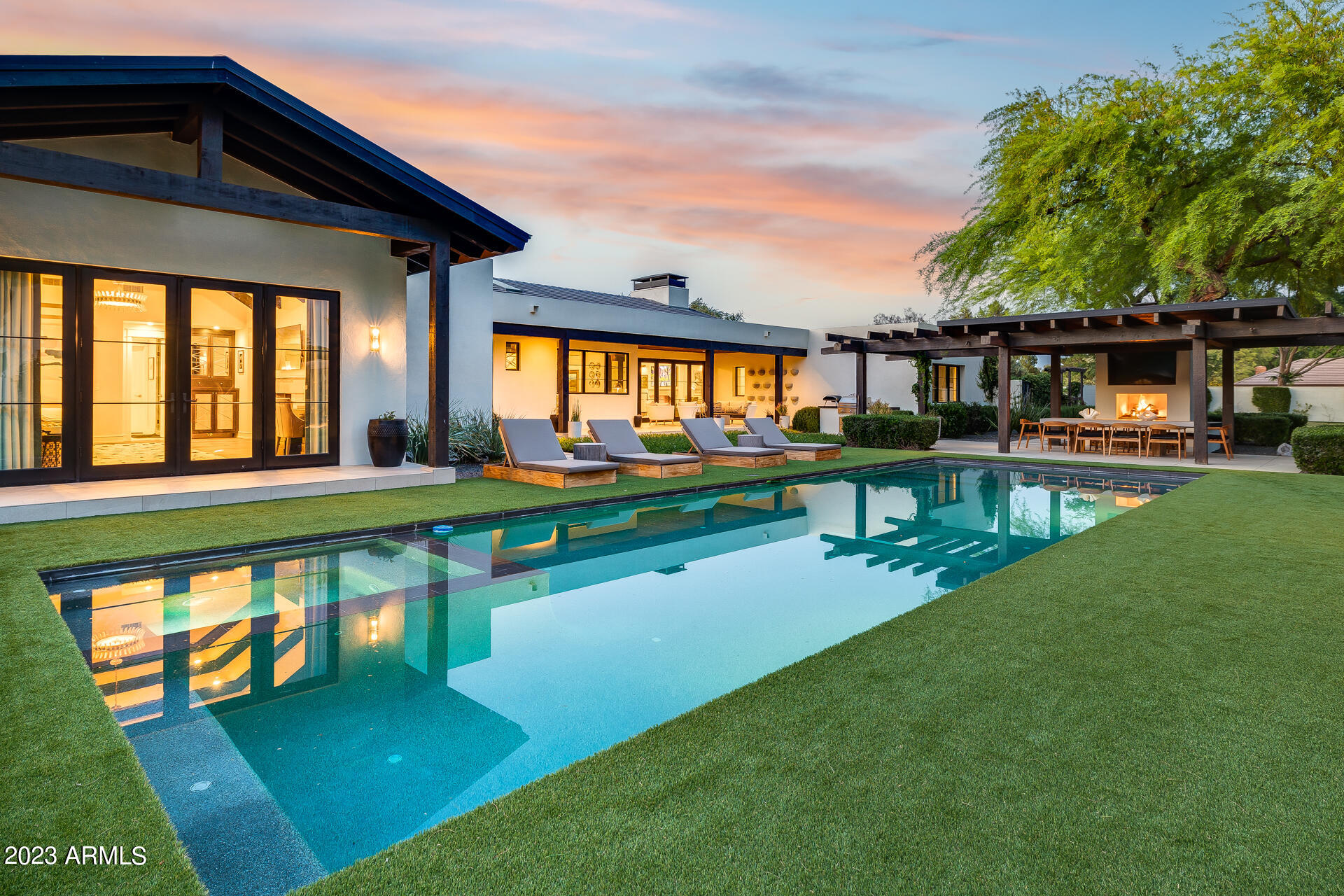 This jaw-dropping South Tempe home is located on a 1.3 acre corner lot in the highly sought after Circle G neighborhood. The home was completely remodeled in 2018 and boasts a number of high-end features and amenities including a custom hand-carved front door, solid core interior doors, and aluminum clad wood exterior windows and doors. Throughout this house you will find exquisite European Oak floors, two custom limestone fireplaces, custom window treatments throughout, motorized privacy shades, designer lighting, and built-in speakers and surround sound. The kitchen is a dream with stained solid rift cut white oak cabinetry, Caeserstone quartz counters, a Sub-Zero refrigerator/freezer and separate ice maker and beverage cooler. But the real star of this kitchen is the La Cornue range and custom metal hood. The primary suite has a cozy fireplace, marble bathroom floors and freestanding tub as well as two spacious custom walk-in closets. The home is a desirable split floor plan and the extra bedrooms feature California closets and ensuite bathrooms. The 1,646 sq. ft. pool house (which could be converted to a guest house) is designed for entertainment!  This breathtaking space will make you feel like you entered a trendy lounge with its full-size bar and custom glass bar shelving. This indoor/outdoor space has pocketing sliding glass doors and a glass garage door which transitions from the Full Swing Golf simulator to the full-size pickleball court. The home's landscaping, designed by Refined Gardens will make you feel like you have entered a resort. The design includes a large covered back patio and covered dining area, outdoor fireplace, built-in grill, large format tile pavers, in-ground trampoline, oversized heated pool and spa as well as a cozy custom stone firepit for those beautiful Arizona evenings. You will be wowed by the mature Mesquite and Ash trees which add to the beauty of the landscape and provide much needed shade in the summer months. No expense was spared on this immaculate property, making it an ideal choice for those seeking a luxury turn-key home.