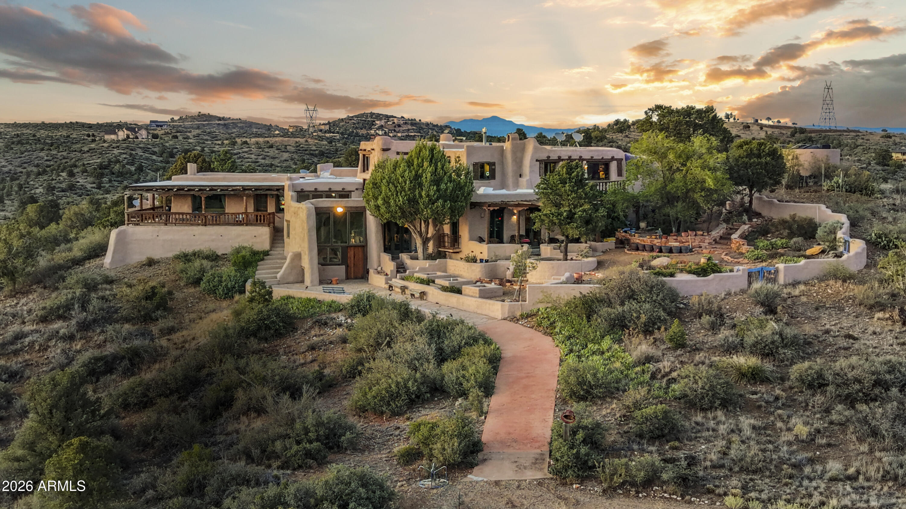 Perched on 40 private acres north of Prescott, this extraordinary hand-built adobe estate is one of Arizona's most singular properties. Views extend in every direction -- mountain ranges, open valleys, and the sweeping Prescott basin. 
Inside, massive hand-hewn vigas and latilla ceilings set the tone throughout. Thick adobe walls frame corner kiva fireplaces in the living spaces and bedrooms alike. The primary suite offers its own kiva fireplace, a grand walk-in closet, a great kitchen with soapstone counters, a 45'' Cafe gas range, wide mountain views, and private outdoor access. 
Each space carries distinct character -- panoramic views, flagstone floors, and adobe benches in the kiva..  A library-lined office loft with bold red walls and floor-to-ceiling bookshelves completes the pictu A detached guest house with covered deck sits just below the main residence, offering privacy and independence while remaining connected to the property's sweeping views. Adjacent to the guest house, there is a studio apartment with a living room, fireplace, bathroom and small kitchen. The former barn has since been converted to office space and the room repurposed for storage, but the infrastructure is in place for a buyer looking to build out a working equestrian facility.  
This is not a home that was decorated -- it was lived in, deeply and authentically. Properties like this are not built anymore. They are simply passed on.