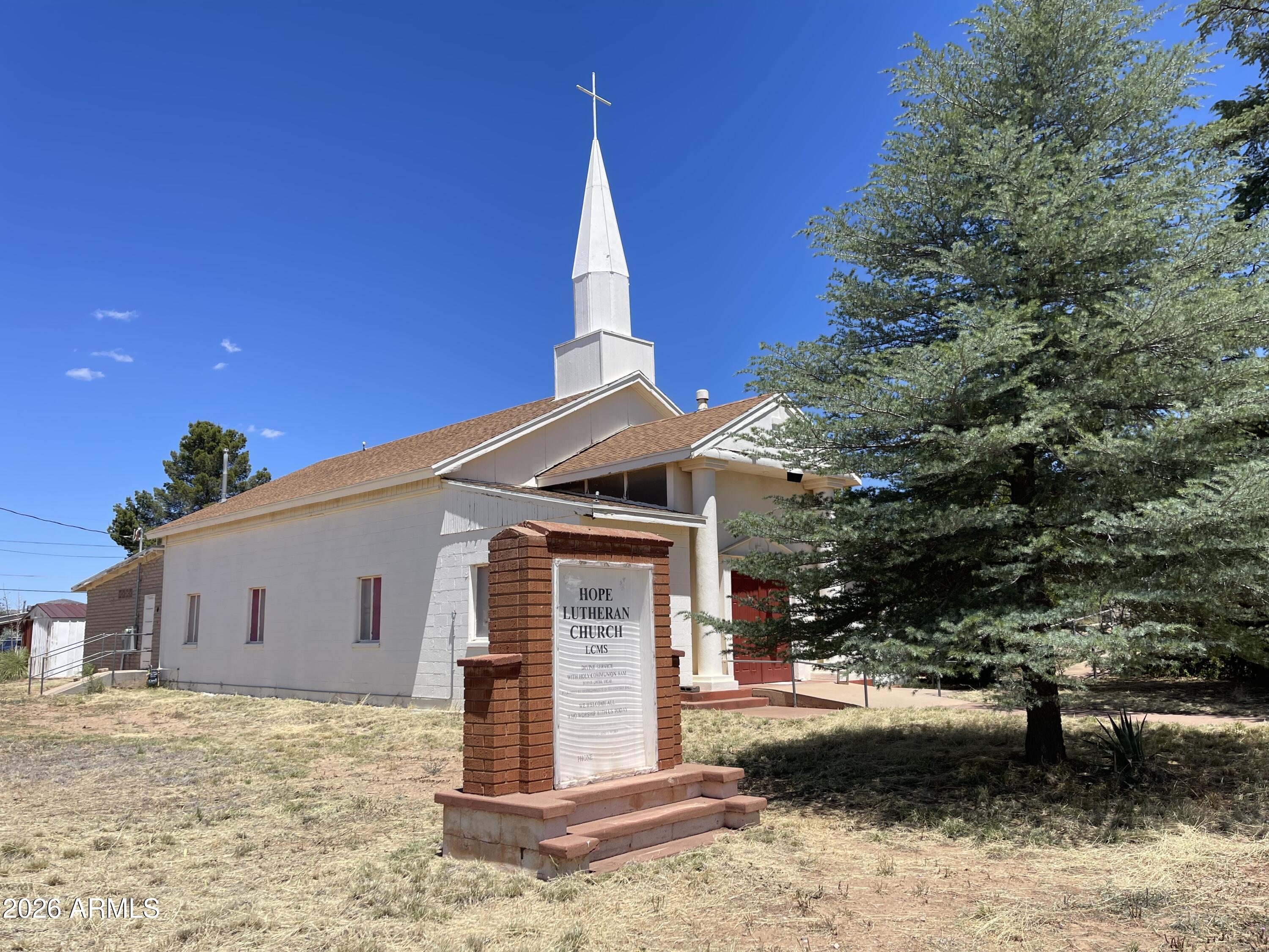 This former church sits on a large lot (.961 acres), tucked back in the Sunset Acres neighborhood of Bisbee. Fully fenced in, the property features two buildings, several large, established trees, and plenty of space for off-street parking. One building holds the main sanctuary, with several small storage rooms, offices and bathrooms. The second building includes a large kitchen, meeting rooms and additional bathrooms. There are so many creative possibilities for what this property could become next with your vision and TLC. Property is being sold, as-is. Seller has very little knowledge or history pertaining to the property, so it is highly recommended that buyers conduct thorough due-diligence and inspections of both buildings, systems, septic, etc. Buyer to verify all facts and figures.