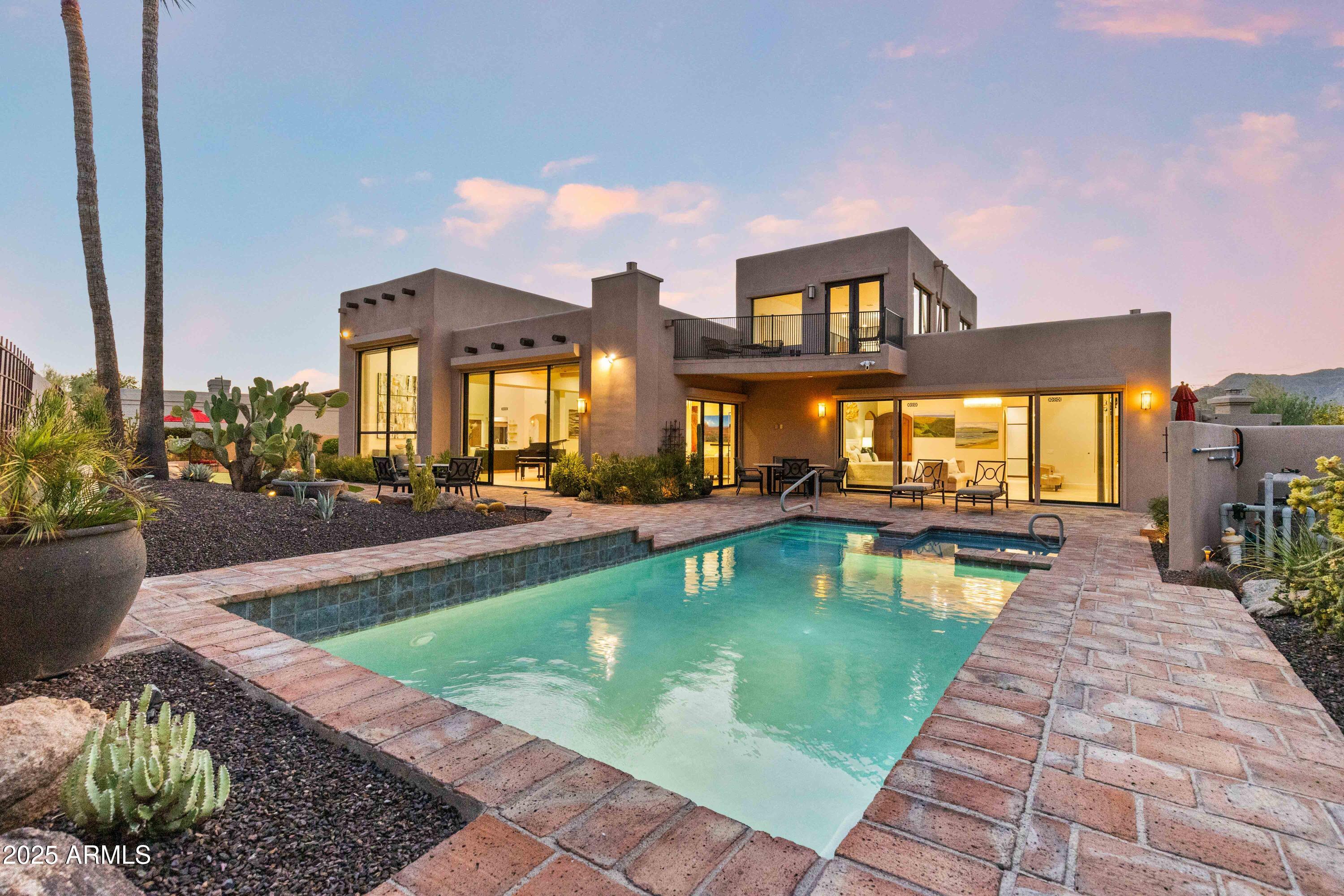 Welcome to this stunning Echo Canyon retreat, reimagined in 2020 with timeless Southwestern architecture and unobstructed canyon views. Floor-to-ceiling windows create seamless indoor-outdoor living. The resort-style backyard features a heated pool and spa, putting green, built-in BBQ, gas fireplace, fire pit, and multiple entertaining areas on one of the largest lots in this gated Phoenix community. The designer kitchen offers walnut cabinetry, quartz countertops, and premium finishes, complemented by hickory hardwood floors. The main level includes a luxurious primary suite, two en-suite bedrooms, plus a private loft suite with its own bath. Enjoy an exclusive party suite with private elevator access--ideal for elevated lock-and-leave luxury living.