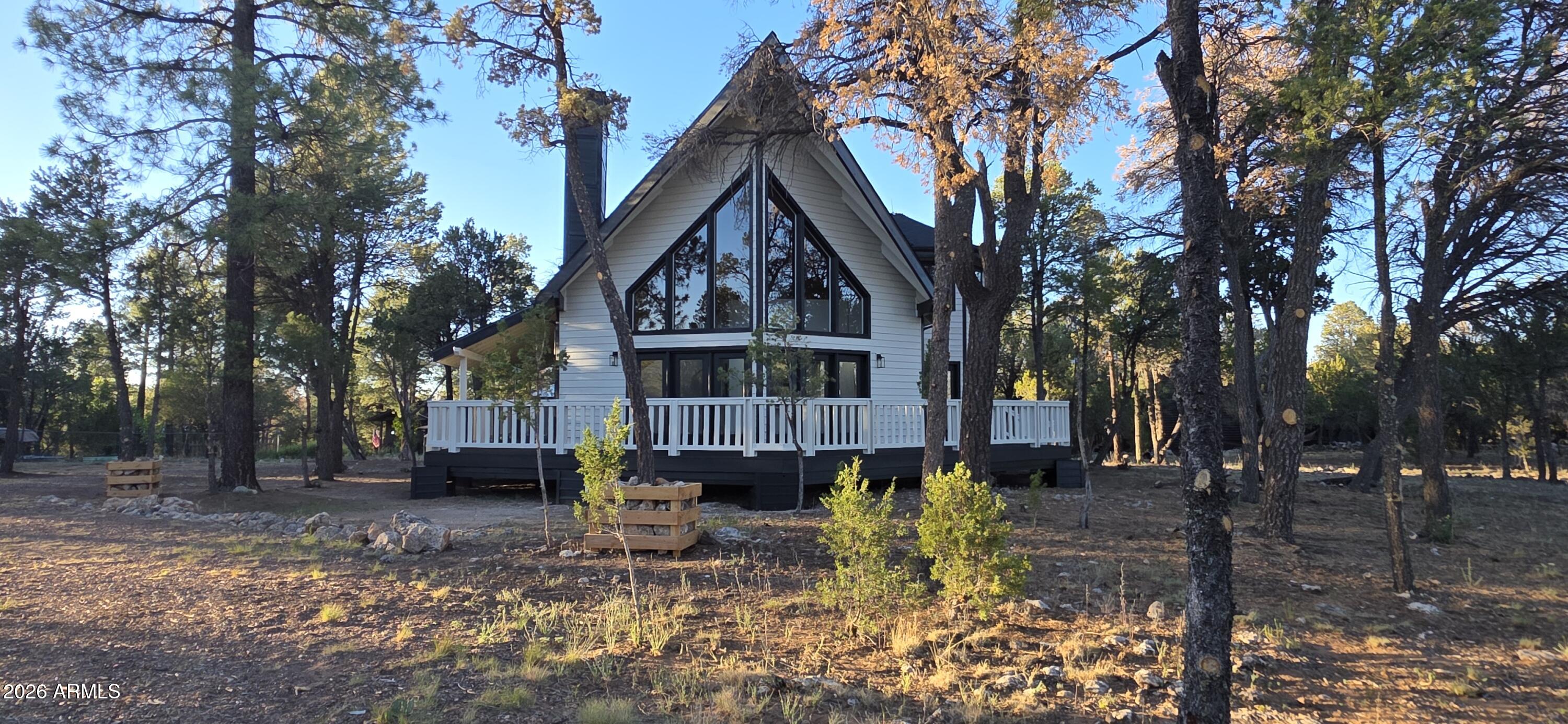 This isn't a cabin. It's a modern A-frame statement in the pines. Contrasting white and black colors make it standout in between the trees.  Large, Clean, Private .81 acre size lot. Featuring an impressive wraparound deck with covered porch and balcony off the primary. Home has unique architecture with a Turret entry with French doors all around the rebuilt deck. Massive A-frame windows provide natural light throughout great room. Property was completely remodeled from the studs, featuring new drywall, Comp Roof, HVAC & Ducting, wood like LVP flooring, sage green kitchen cabinets with pulls, beautiful Quartz countertops with Gold veins, tile showers with pebble flooring, a stand alone tub in the primary, vaulted wood T&G ceilings, soaring fireplace with stone, a custom mantle and shiplap. Upgraded trim and closets, New interior doors, hardware, fans and lighting as well as electrical and plumbing upgrades throughout the property. What a drastic change, check out the before and after pictures.