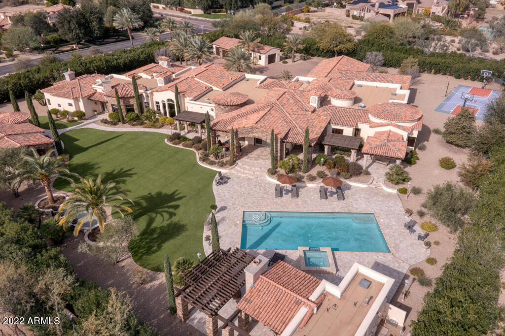 This luxurious 2.3 ACRE gated Mediterranean-inspired PRIVATE COMPOUND, includes a 2 bedrm full guest house, ramada w/ kitchen & bath, huge grass areas, basketball court, pool, & 2 structures for 6-9 cars. ALL SINGLE LEVEL, it includes a home theatre, billiards room, library, exercise rm w/ remote access switch to master steam shower, 22ft bonus rm, large master w/ fireplace & huge his/hers closets---split from a guest wing with 3 ensuite bedrms, 1 is a mother-in-law suite w/ its own kitchenette. The magnificent family rm has expansive pocket doors & both bar and wine rm, which opens into a gourmet kitchen. Detailed finishes include stone & hardwood flooring, intricately detailed stone fireplaces & custom domed ceilings. Fire & water features make this dramatic resort really memorable!!