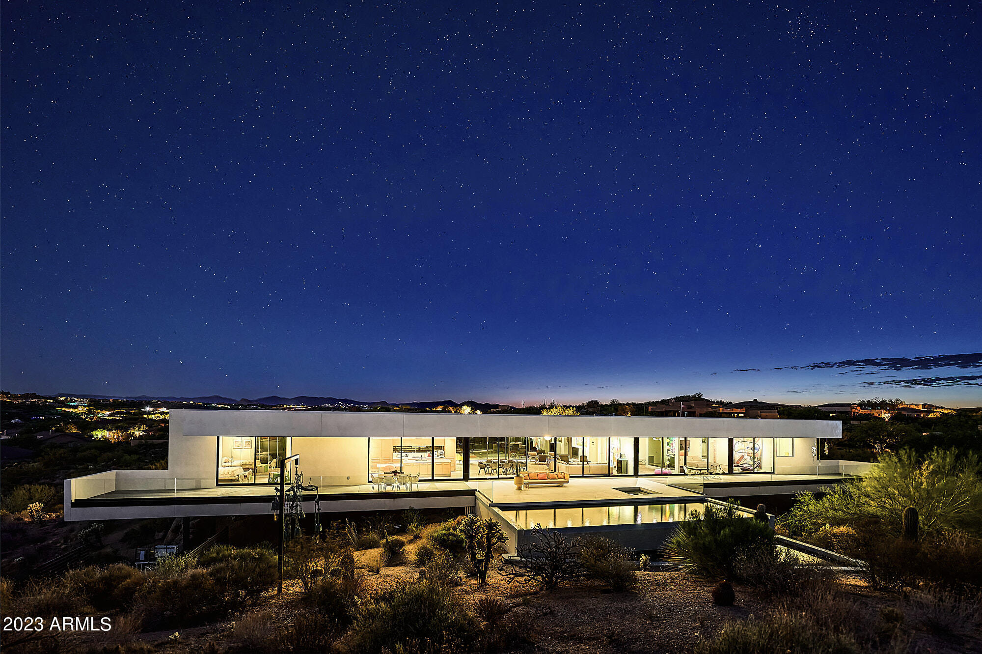 This architectural gem has a beautifully simplistic and contemporary design, breathtaking views, blends seamlessly into the desert and was created by one of the most recognized modernist architects of our time, Michael P Johnson. Made of steel and glass, this home is positioned to float over the delicate desert landscape as to not disturb it, creating the spacious living area that offers privacy and peaceful living. Every room in the house shows the views you've always dreamed of having! 
A glass pivot front door leads to white Italian porcelain flooring, clean lines, and surrounding mountain views. A 54-ft glass wall slides open to offer a negative edge heated pool and spa and 185 ft deck. This home exudes a peaceful and tranquil atmosphere throughout. This could be your paradise!