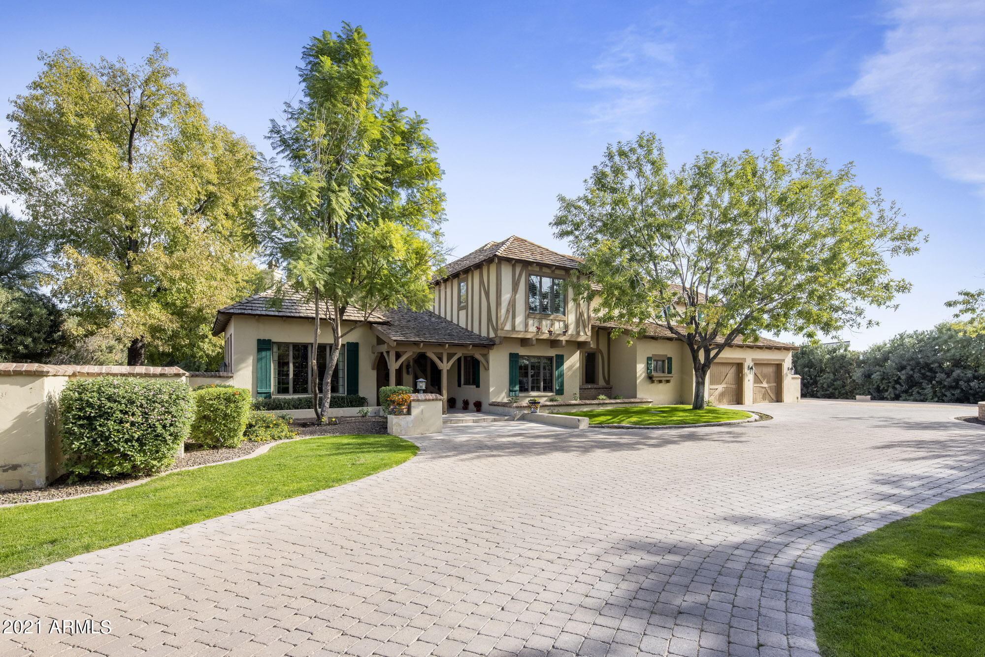 Tucked away behind iron gates, enveloped by tall trees and mature landscaping for privacy, this magical hidden gem will amaze you. A custom home right out of a fairytale with a pavered driveway, rolling hills, enchanting front door, vaulted beams and endless character. The main house features a cozy living room with stunning Camelback mountain views, an onyx fireplace mantel, an oversized family room with a soaring ceiling and a grand office space. Gourmet kitchen with high end appliances and casual breakfast nook. The upstairs master suite is the perfect relaxing space with a gas burning fireplace and viewing deck overlooking the entire backyard. All secondary bedrooms are generously sized and feature private bathrooms.  Detached guest house offers a full kitchen, living room, en-suite bedroom, powder room, laundry room and single car garage. The lush grounds are perfect for hosting and features a rose garden, a sparkling pool, sport court, outdoor kitchen and plenty of shaded covering. Schedule your private showing now for the storybook ending you've been dreaming of.