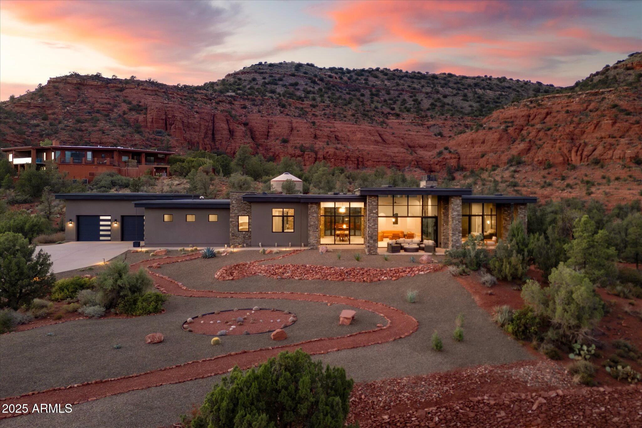 Experience the extraordinary—a NEW construction 4,446 sq. ft. estate on 1.76 acres with epic 360-degree views of Sedona's iconic Red Rocks, surrounded by National Forest land, and no HOA. Offered fully furnished - move right in or begin earning vacation rental revenue on Day One & ENJOY the peace of mind that comes with a NEW HOME! 

Welcome to 305 Sacred Eagle—a brilliant masterpiece of desert-modern architecture, tucked away on a private drive off Sedona's famed Red Rock Loop. Where floor-to-ceiling 14-foot walls of glass provide a seamless Sunrise-to-Starlight connection to Sedona's awe-inspiring vistas. Where the best open-concept design trends are perfectly executed. Where bespoke finishes exude sophistication, and curated details envelop you in quiet luxury. Every aspect of this estate has been thoughtfully planned & flawlessly executed to provide the ultimate, exclusive Sedona retreat. Walk through the 12-foot-tall pivot glass entry door and into the flow of outstanding modern design. Relax in the gorgeous great room featuring a stacked stone gas fireplace, 85-inch 4K TV, and multi-slide glass walls that merge indoor luxury with outdoor beauty. Create lifelong memories around the 10-foot dining table with abundant entertaining space and sweeping red-rock views. 

Experience the ultimate kitchen flexa space that can accommodate large groups while maintaining an efficient work triangle for seamless meal prep. Bonus points for the separate pantry, computer nook with TWO custom desk spaces, and extraordinary 10' × 6' superslab honed quartz island!

The grand hallway stretches more than 70 feet as you walk past dramatic stacked stone columns and illuminated art niches on the way to four luxurious bedrooms and a spacious media/game room. EVERY bedroom features bedside crystal pendant lighting, an integrated, custom headboard, and a spacious walk-in closet with built-in cabinetry that includes drawers and separate hamper space. 

All three full bathrooms feature a private water closet, quartz counters, wall-mounted faucets, LED backlit mirrors and a glass-enclosed walk-in shower with dramatic porcelain-tiled walls and pebbled shower floors. An additional half-bath features a live-edge Juniper countertop and custom stone sink bowl.

The Primary Suite is a retreat unto itself. Spend cozy evenings enjoying the 72-inch gas fireplace flanked by artful floating shelves. Catch your favorite show on the 4K LED TV above. Gaze out through 12-foot-high walls of glass and walk through double French doors onto the Primary Suite's covered patiothe perfect spot to experience Sedona's BEST sunrises.

The primary ensuite combines spa-like tranquility with impeccable functionality. Unwind in the pebble-surrounded freestanding tub while soaking in red rock views through floor-to-ceiling windows. The walk-in shower boasts the same stunning views and an additional separate door to your own private OUTDOOR shower experience. Every detail has been carefully curated to enhance your daily rituals. You'll find an abundance of counter space, dual vanities, a dedicated, illuminated seated make-up table, and TWO separate walk-in custom closets. This primary ensuite sets the standard for luxury and livability.

Outside, a nature lover's paradise awaits. Enjoy morning coffee on the Grand Patio with its comfortable seating area. Take off in multiple directions for endless hiking on National Forest trails, including several of Sedona's stellar standouts. Ascend the striking Cimarron Butte, where you can capture epic views of majestic Cathedral Rock, the heartbeat of Sedona. Close your exercise ring on the perfect morning loop around Pyramid Trail. 

Back home, stroll the meticulously landscaped grounds, where every element has been crafted to inspire tranquility and balance. Experience pure magic from your front yard as the red rocks glow in sunset light and a meditative Medicine Wheel awaits, its four cardinal directions outlined by carefully placed stones. Find your center in this tranquil space, designed for self-reflection and inner harmony. Gather fireside under the back lanai while the outdoor chef prepares dinner nearby on the built-in Napoleon gas grill. 

The energetic centerpiece of this special property is the dynamic outdoor bronze sculpture "I am Sacred Eagle" by acclaimed artist John Benedict. A sacred symbol in many Native American traditions, the eagle is revered for its strength, courage, wisdom, and freedom. Come experience this and more at this extraordinary property. 

Additional features of note include:

- Sold fully furnished with all indoor and outdoor furniture, decor, artwork, televisions, sound systems, gaming tables and equipment, bedding, linens, pillows, kitchenware, tableware, and more
- 4' x 12' Glass and Steel Pivot Door for Front Entry
- Tongue and Groove wood ceilings in Great Room, Dining Room, Primary Bedroom, Outdoor Grand Patio, Owner's Suite Patio, Rear Promenade Patio and Fireside Patio
- Natural stone columns interior and exterior 
- Whole house water softening system
- Reverse osmosis drinking water filtration
- Fire suppression system with onsite water storage tank
- Two-car garage with lock-off for one car spot and epoxy flooring in both garages
- Two Primary walk-in closets, one closet can be locked for owner's storage
- Two walk-in closets, with one lock-off in additional guest room
- Motorized blinds in Primary Bedroom
- Large capacity LG Smart Washer and Dryer (electric)
- Separate plumbing for gas at dryer location
- Dark sky compliant outdoor lighting package