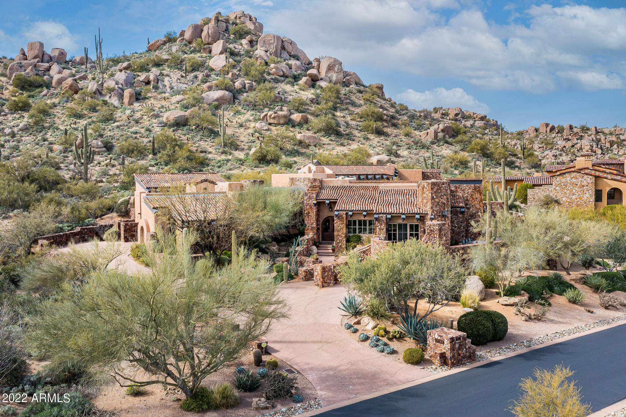 Timeless Desert Contemporary-design sited on an elevated lot at the base of Pinnacle Peak in Estancia * Designed by Terry Kilbane, this warm and inviting home offers panoramic mountain and golf course views * Split floor plan with a great room, oversized primary suite, two large guest suites and a dedicated office * Exterior architectural elements include a blend of dry-stacked stone, stucco, wood and glass that integrate seamlessly with the desert surroundings * The interior details include stamped concrete flooring, dry-stacked stone walls, light and bright venetian plaster, wood beam and tongue & groove ceilings, custom alder cabinetry/doors and multiple dry-stacked stone fireplaces * The outdoor living includes a large patio with golf course and mountain views, built-in BBQ station, heated spa and artfully designed water feature *