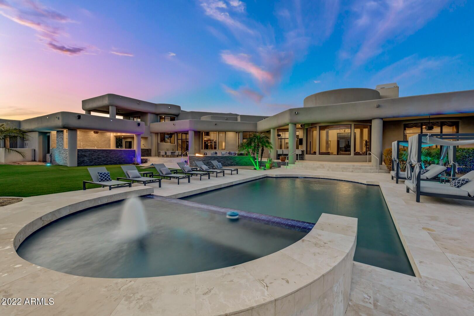 With over 8,000 sq feet of luxury, this desert oasis boasts massive 18 ft ceilings, a custom split floorplan, and seemingly unlimited storage. Nestled on a corner lot with over 2 acres of land, this home offers 2 studies, a theatre room, and smart home capabilities with Ruckus WiFi and a Bowers & Wilkins sound system throughout. The primary suite resides on the main level with picturesque views of the resort style backyard. Inside the primary bath you will find his and hers toilets with a bidet, oversized counter space, a rain head shower and a jetted tub. Conveniently located off of the primary suite lies an exercise room with access to the back patio. Three additional bedrooms are located upstairs in the main home with elevator access. Each additional bedroom accompanies an en suite.. bath and walk in closet. In the detached casita, you will find two bedrooms separated by a Jack-and-Jill bath along with a kitchenette and laundry. The backyard offers a brand new commercial grade built-in kitchen, built-in bar, and mister system to overlook the pool and spa. This home is an entertainer's dream with no HOA. Close to freeways, shopping, and dining. Schedule your private viewing today!