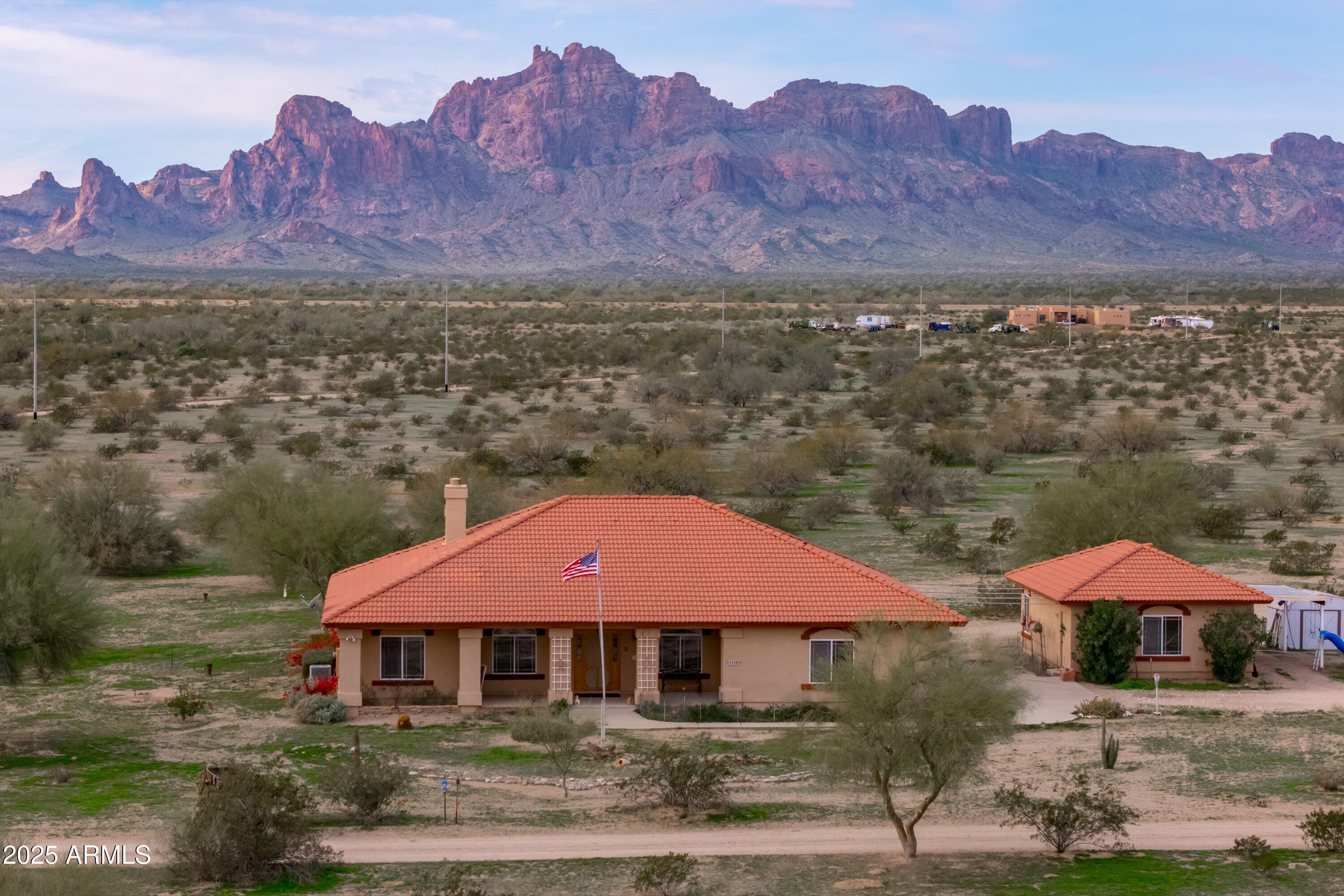 Spectacular 40-acre ranch offering privacy, breathtaking mountain views, and true Arizona living! This stunning 4-bedroom, 3-bath, 2,336 sq ft home features 2x6 walls, a formal dining room, a cozy fireplace, and an additional flex space perfect for an office or sitting room. Expansive windows frame the incredible Tonopah scenery, with saguaros as your only neighbors. Beautiful flooring flows throughout the home, complemented by abundant storage, real wood cabinetry with pull-outs, a charming office nook, and built-in Craftsman-style bookshelves surrounding the living room TV area. Enjoy covered patios on both the front and back of the home, a large 2-car garage, and a massive detached workshop that can also serve as additional garage space. Ideal for horses, hiking, and wide-open living