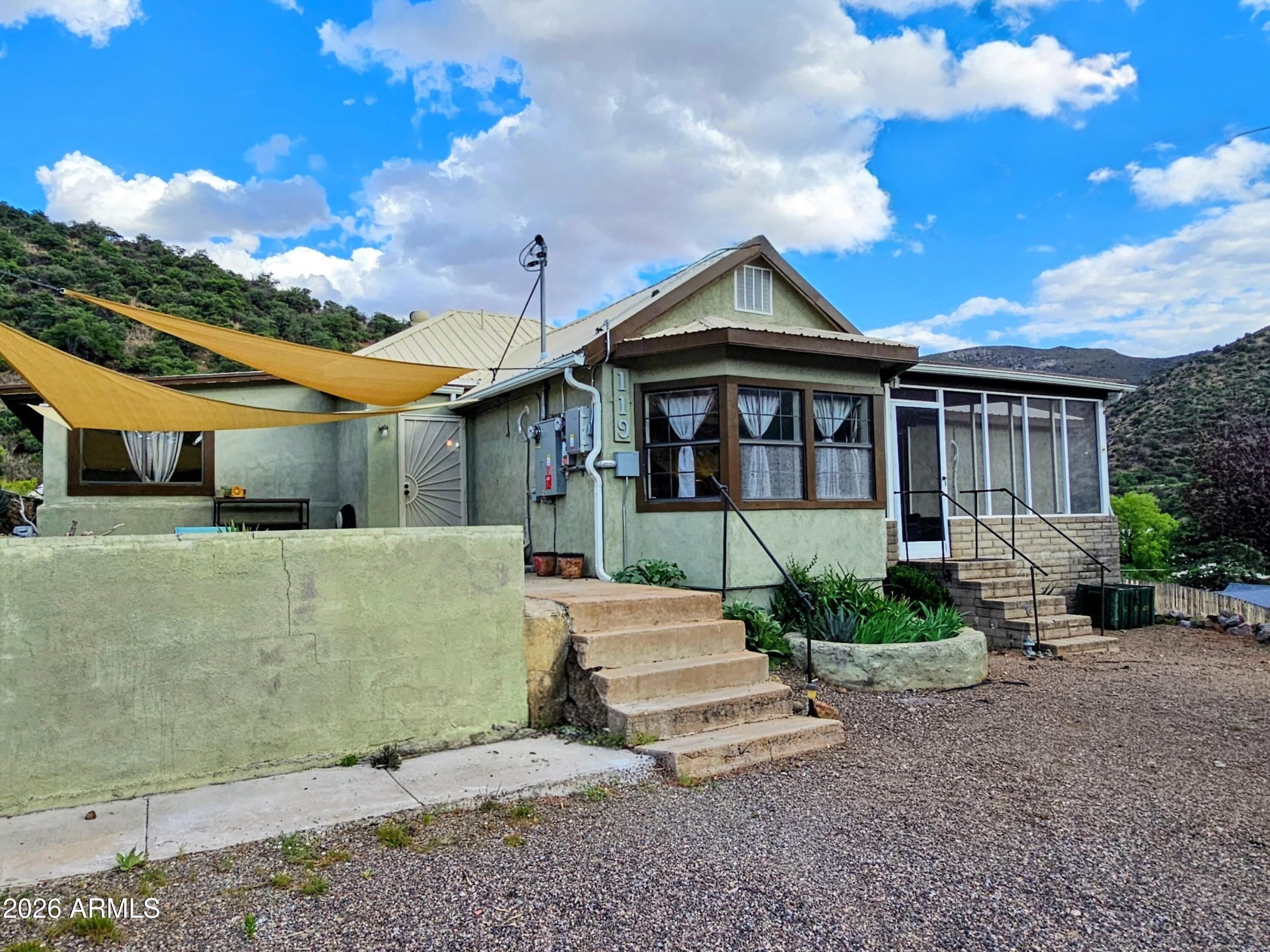 Old Bisbee: Spacious 2,226 sq. ft., 3 Bedroom, 2 Bath with Large, Level Dedicated Parking Area (space for at least 6 cars), Great Views of the Mule Mountains, Lanai, Fenced Yard, Courtyard, and Private Well for Irrigation,  on .36 Acre. Originally built in 1933, added onto and improved over the years, with Grid-Tied Solar Panels, 200 Amp Electrical Panel, 5 Mini-Splits for efficient Heating and Cooling, Metal Roof, Dual Pane Windows and a vast, 750 sq ft Living Room/Great Room with Oak Flooring, and a Gas Fireplace.