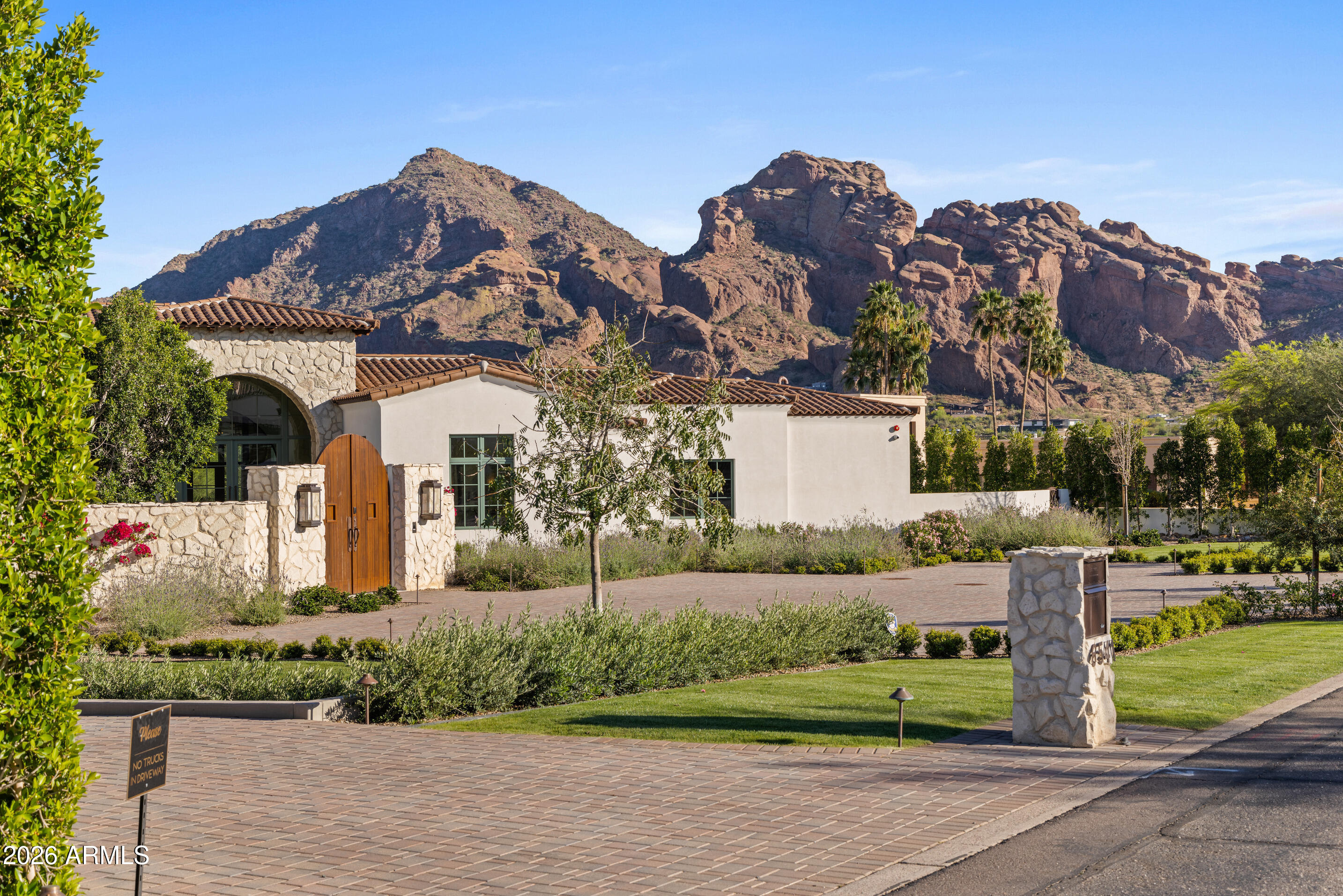 Newly built in 2025, this exceptional Paradise Valley residence blends a refined transitional style -- melding the warmth of Santa Barbara architecture with modern design plus top-tier finishes -- and captures dramatic views of Camelback Mtn, including the Praying Monk and Head of Camelback. The great room features soaring 18-foot ceilings and a dramatic Italian tile fireplace, opening to outdoor living with a fully tiled negative-edge pool, manicured lawn, and a premium Hestan grill and pizza oven. The chef's kitchen is anchored by BlueStar appliances, a spacious back kitchen w/ additional appliances + walnut Artitalia cabinetry with special organizers. A luxurious primary wing offers a unique glass sauna with contiguous glass steam shower, dual towel warming drawers, 2 large closets... plus a long glass shelved hallway to showcase handbags. Crestron automation, Palecek lighting and quartzite cristallo counters Enhance the sophisticated feel of the home. Additional highlights include a large brick ceiling wine room, a theater, office, mudroom cabinetry and dog wash station.