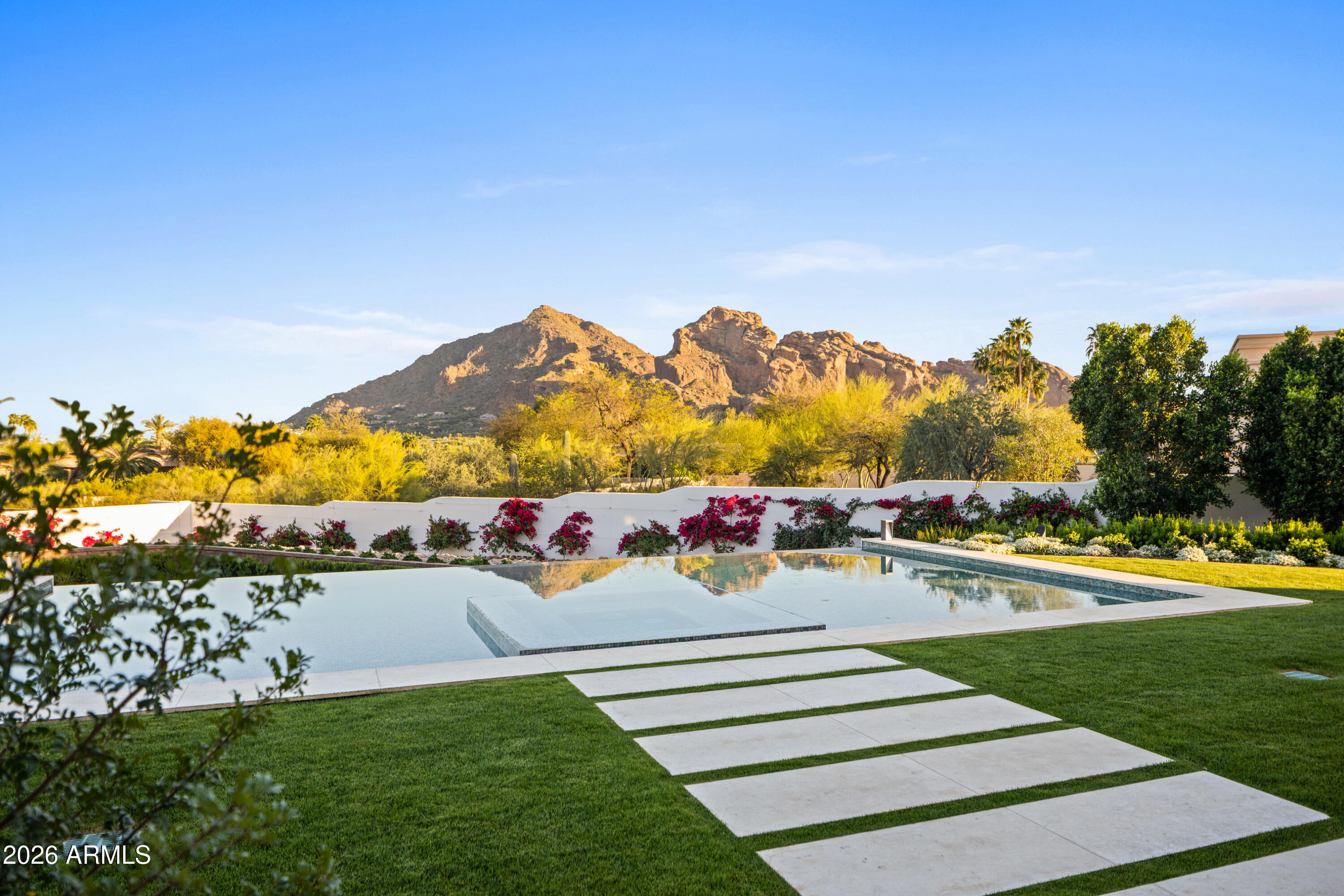 Newly built in 2025, this exceptional Paradise Valley residence blends a refined transitional style -- melding the warmth of Santa Barbara architecture with modern design plus top-tier finishes -- and captures dramatic views of Camelback Mtn, including the Praying Monk and Head of Camelback. The great room features soaring 18-foot ceilings and a dramatic Italian tile fireplace, opening to outdoor living with a fully tiled negative-edge pool, manicured lawn, and a premium Hestan grill and pizza oven. The chef's kitchen is anchored by BlueStar appliances, a spacious back kitchen w/ additional appliances + walnut Artitalia cabinetry with special organizers. A luxurious primary wing offers a unique glass sauna with contiguous glass steam shower, dual towel warming drawers, 2 large closets... plus a long glass shelved hallway to showcase handbags. Crestron automation, Palecek lighting and quartzite cristallo counters Enhance the sophisticated feel of the home. Additional highlights include a large brick ceiling wine room, a theater, office, mudroom cabinetry and dog wash station.