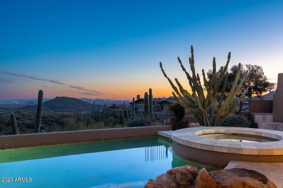 Custom built, one owner home in prestigious Saguaro Forest village of Desert Mountain Golf & Recreation Club. Spectacular panoramic views down the mountain of city lights, winter sunsets and mountain views. Built by Platinum Homes, the quality is obvious throughout the large living room with fireplace, flowing into the kitchen with large, natural edge granite island, walk in pantry, large dining area, all looking out to the south facing views. The 800 bottle wine room is adjacent to the sunken bar and convenient to the outdoor entertaining space with zero entry pool , spa, and generous seating next to the outdoor fireplace to take in the massive views while staying warm. Ample covered, expansive patio space has plenty of shade in the warm months and sun exposure on the pool. Four ensuite bedrooms, plus large office with private entrance, this home is efficiently powered with the help of 72 owned solar panels. Oversized 3 car garage offers abundance of storage.  

More on Desert Mountain... It is a thirty-four-year-old, 8,200 acre, gated, world famous private golf and outdoor recreation-oriented master planned development on the slopes of the Continental Mountain range on the northern edge of Scottsdale, contiguous to the fourth largest National Forest in the country. There is a twenty-mile private trail system in these mountains for the exclusive use of Desert Mountain residents. The top elevation is 4,890', highest in all of Maricopa County. The views from the high point in the trail system are really something to see! Phoenix Sky Harbor Airport is typically about a forty-minute drive from the community's Front Gate. 

The opportunity to be a member of The Desert Mountain Club is a significant part of the attraction of living in Desert Mountain for most property owners as the Club is the emotional, physical, and social "core" of the place. The Club is rightfully internationally famous as a year 'round, private spa and golf mecca, with seven clubhouses, nine dining venues, six eighteen-hole championship Jack Nicklaus Signature courses, four practice ranges, a high-tech golf performance center, and an eighteen-hole par-3 course, rated for handicap purposes. That course, known as "Seven", has a "sports bar" clubhouse with twenty-eight big screen televisions, two bocce ball courts, and several huge firepits. 

One of the other Clubhouses is the Sonoran Clubhouse, an amazing swim (three pools), tennis (nine courts, including grass, Har-Tru, and cushioned surface hard courts), fitness, and spa facility with a grill restaurant. It enjoyed a $12,000,000 renovation in 2016. The following summer saw six pickleball courts, two bocce ball courts, and a croquet court added. It is now perhaps the premier facility of its type in the entire Southwest.

The Club's dining venues offer a wide variety of food, wine, and atmospheres. No coats and ties required! A tremendous range of non-golf outdoor recreation and social activities are also available. The Club's membership is catered to relentlessly by an attentive Club staff and Concierge, providing unparalleled service. In a word, the place is "phenomenal". It is so good, three multi-million-dollar lottery winners have chosen Desert Mountain over the years as the place they want to live.

Desert Mountain is a place of surpassing scenic beauty with long-range, panoramic views of Phoenix, Scottsdale, the entire "Valley of the Sun", many mountain ranges near and far, and, of course, Arizona's famous sunrises and sunsets! It has attracted full-and part-time residents from all over North America, Great Britain, and western Europe. Another reason people like to own real estate here is because real estate taxes are strikingly low compared to many parts of the country, particularly the Northeast, Midwest, and California. The weather is famously sunny, and our risk of natural disasters is extremely low. Being higher and somewhat removed from the city means the stars are bright at night and the air is typically much cleaner than what lies over the Valley.

Day-to-day shopping needs for Desert Mountain owners are well-handled within about a ten-minute drive by the merchants in the nearby towns of Carefree and Cave Creek. There are 69 restaurants and bars within about sixteen minutes' drive. The Phoenix/Scottsdale area is famous for world-class shopping, major league and collegiate sports, terrific air service, and a wide variety of cultural attractions. Desert Mountain is within two and a half hours of normally excellent snow skiing in Flagstaff. Its location in the southwestern part of the United States affords easy access to the entire American West, with especially easy access to San Diego, Los Angeles, Las Vegas, the Grand Canyon, Lake Powell, and a plethora of unbelievably beautiful places in Southern Utah. "Paradise" doesn't overstate it.