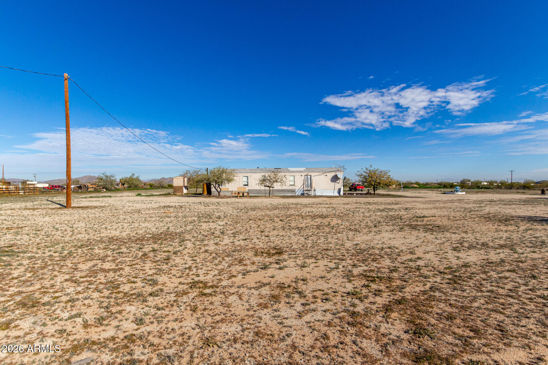 Welcome to Mi Lindo Sueño! This 3+ acre ranch sits at the peaceful outskirts of Maricopa, offering beautiful mountain views and serene country living while remaining conveniently close to city amenities. The manufactured home features a semi-open floor plan with vaulted ceilings that create a bright, airy atmosphere, a spacious kitchen with abundant storage & appliances, and a primary bedroom with a bathroom. Step out to the back porch to an ideal spot to relax and enjoy spectacular sunsets. The expansive land includes multiple storage sheds and ample space for horses, livestock, and your vision of ranch life. Whether you're seeking a peaceful retreat or room to grow, this property offers endless potential to create your own ''Lindo Sueño''. Property has a water tank underground with pump