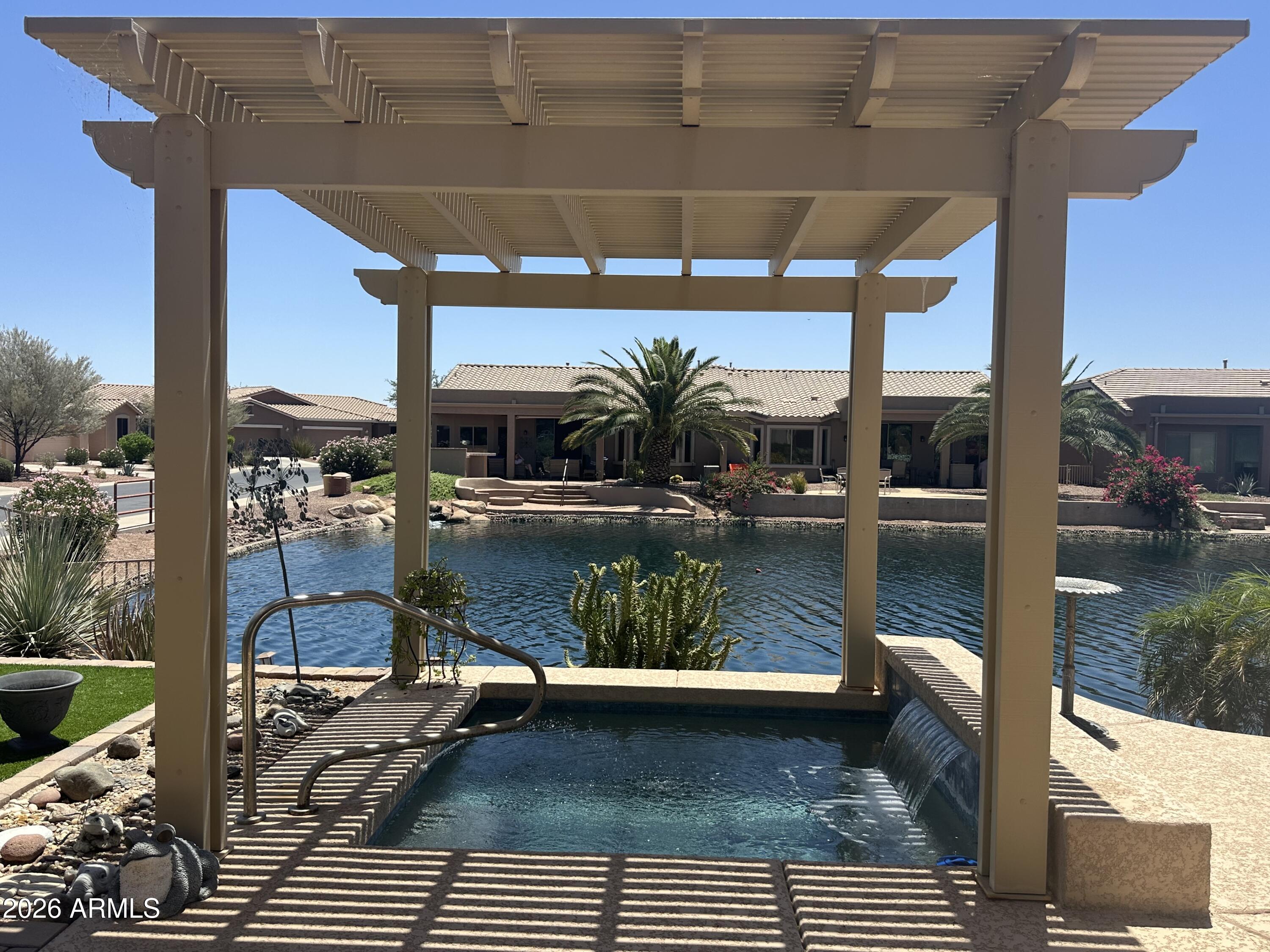 WATERFRONT! Backyard is WEST facing!  Charming 2 BR 2 BA + Den (w/ barn door closure)  Villa on the water and on a coveted corner lot. This home has personality plus! Kitchen has gorgeous granite countertops, pantry, dbl-oven gas range. Living area has a floor to ceiling rock feature wall with a built-in electric fireplace. Primary bath has striking bowl sinks and vanity. Garage has easy-care epoxy floors. Sun lovers can luxuriate in the backyard and sip a favorite beverage from the spool-a dipping pool when you want to cool off, and a bubbly hot tub when you want to unwind. Built-in BBQ with plumbed gas. Stay cool under the patio with commercial misting system. It's resort style living at its finest and the HOA covers roof repairs/replacement, front yard maintenance and ext paint. Province is an award-winning, guard gated, 55+ Adult community with 25 miles of walking paths, meandering lakes and greenspaces, pickleball,
tennis, bocce, basketball, putting green, billiards, crafts, sewing, cafe, resort-style pool, indoor lap pool.  So many activities! It's a wonderful lifestyle!