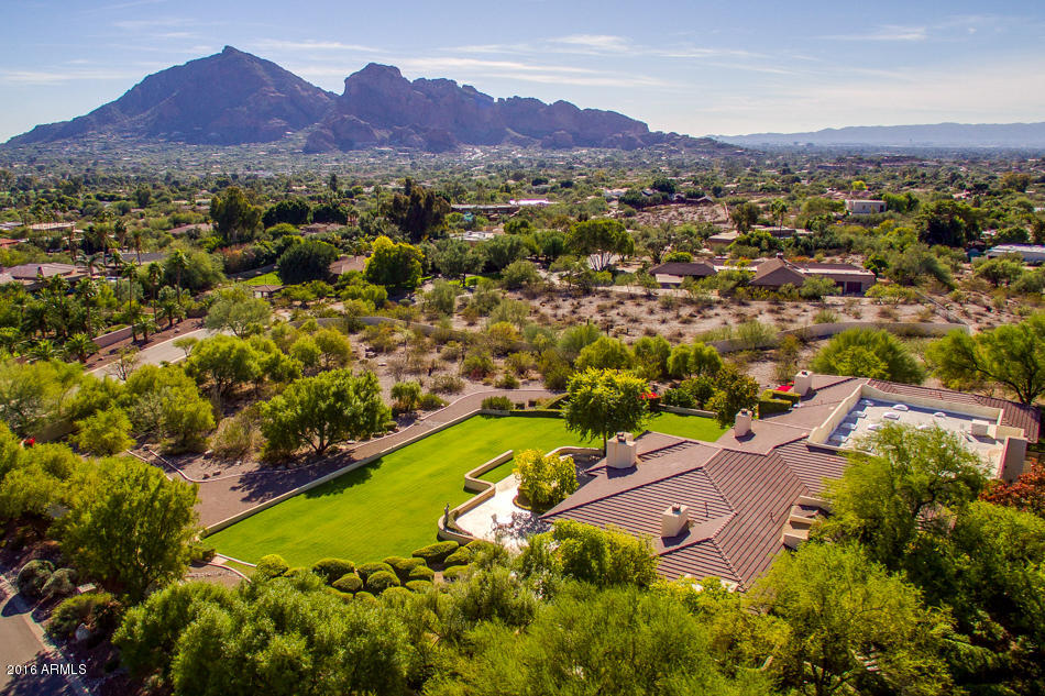 Tucked away on one of the most prime Paradise Valley locations, sits an estate so special, that it was hand-picked for its panoramic views and solitude. Enter thru the private gates and be mystified by the 3+acres lush grounds perfectly mixed with the tranquility of the Sonoran Desert. The prestigious residence, with its perfectly-conceived Frank Lloyd Wright architectural influence is truly a masterpiece before its time. The interior and exterior canvas is the perfect palate for a true art enthusiast. This single level home showcases the historical uniqueness of a renowned visionary coupled with refined craftsmanship. It offers a flexible floorplan with high ceilings thru the commercial grade doors and windows that frame the surrounding mountains as if they were pictures on the walls. The opulent master suite is adorned with a romantic fireplace, his and her separate bath areas and a personal spa room with indoor sauna, jacuzzi and fitness area. The privately walled grounds are the perfect entertaining setting, and the adjacent lot affords the ultimate seclusion and flexibility to separate and create an estate like none other.  Truly an architectural gem surrounded by Sonoran beauty.