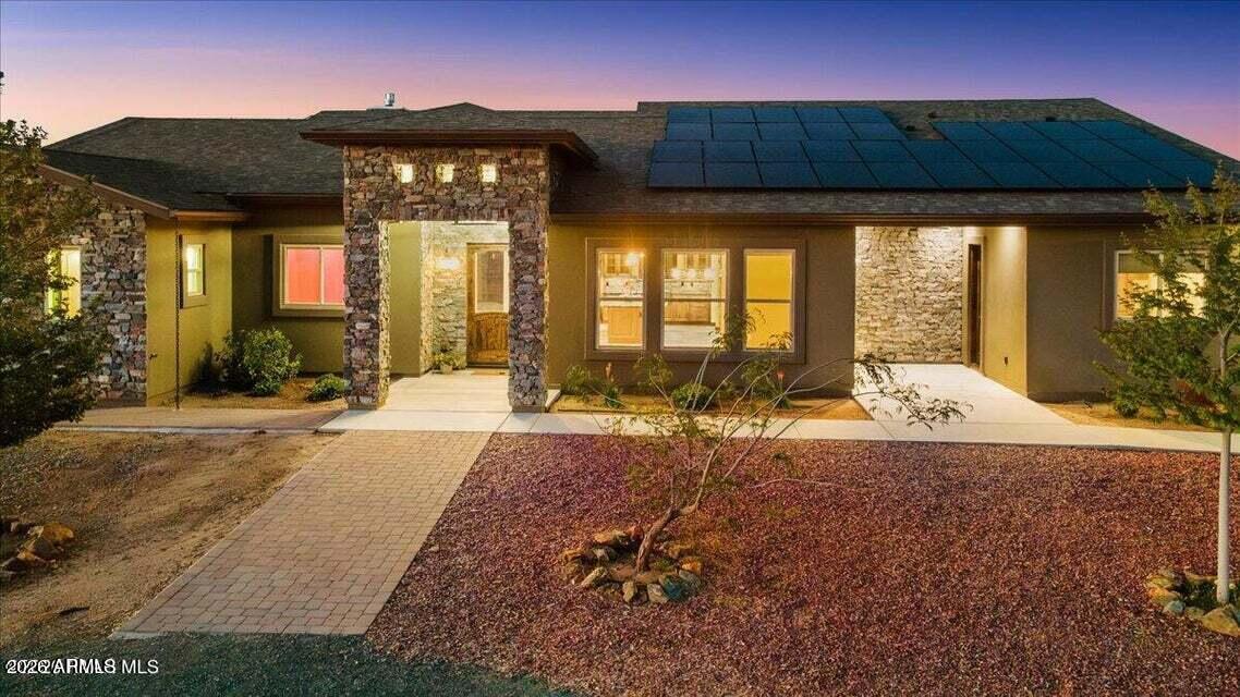Welcome to your private western luxury retreat in Chino Valley, Arizona, where 5 fully fenced acres, San Francisco Peaks views, and turnkey equestrian amenities create an exceptional opportunity for upscale country living. This beautifully designed approximately 2,883-square-foot home offers 3 bedrooms, a private office, and a thoughtfully planned layout that blends comfort, accessibility, and function. Designed for both everyday living and entertaining, the home features a formal dining area, spacious kitchen dining space, large windows, and four sliding glass doors that fill the interior with natural light and showcase the surrounding views. At the center of the home is a standout chef's kitchen with premium Café appliances, double ovens, abundant prep space, a massive 10+ foot leathered granite island, matching leathered granite windowsills, under-cabinet lighting, and a huge walk-in pantry. The living area is anchored by a dramatic floor-to-ceiling rock gas fireplace with distressed wood accents, while the office is framed by soft-close sliding barn doors for privacy and style. Wider hallways and expanded shower entrances enhance wheelchair accessibility. The spacious primary suite offers a spa-like retreat with dual walk-in closets, separate vanities, and a walk-in shower designed for comfort and convenience. Additional features include custom blinds throughout, power blinds in the main living areas and primary suite, a large laundry room with extensive cabinetry, counter space, and a utility sink, plus permanent exterior holiday lighting for year-round ease and curb appeal. Outside, this Chino Valley horse property is built to perform. The oversized 4-car garage features durable epoxy flooring and a rare drive-through design, ideal for vehicles, trailers, side-by-sides, or workshop use, and the property also includes space for an RV with full hookups. Equestrian improvements are extensive, including a 2,000-square-foot mare motel with concrete flooring, rubber mats, power and water at every stall, full lighting, hay storage, enclosed tack room, and a concrete bathing station. Previously used as a boarding facility, the property is well suited for horse training, roping, team penning, boarding, or recreational riding, with a 60-foot round pen and a 130' x 230' riding arena already in place. A major bonus is the approximately 1,200-square-foot geothermal greenhouse, equipped for year-round growing with water, lighting, dual water walls, geothermal-powered cooling fans, exhaust fans, and adjustable roll-up sides for efficient climate control. The large, covered patio overlooks growing trees, green grass, and open skies, creating the perfect setting for outdoor dining, entertaining, or quiet evenings at home. Additional highlights include exterior rockwork, hot and cold outdoor water faucets, full irrigation and drip systems, water access throughout the property approximately every 100 feet, solar for improved efficiency, pipe fencing, a fenced backyard for smaller animals, and two gated entrances, including one with a solar-powered gate opener. With luxury finishes, usable acreage, equestrian functionality, greenhouse versatility, privacy, and panoramic views, this property offers more than a home--it offers a rare Arizona ranch lifestyle built for riding, entertaining, growing, and enjoying the very best of modern western living.