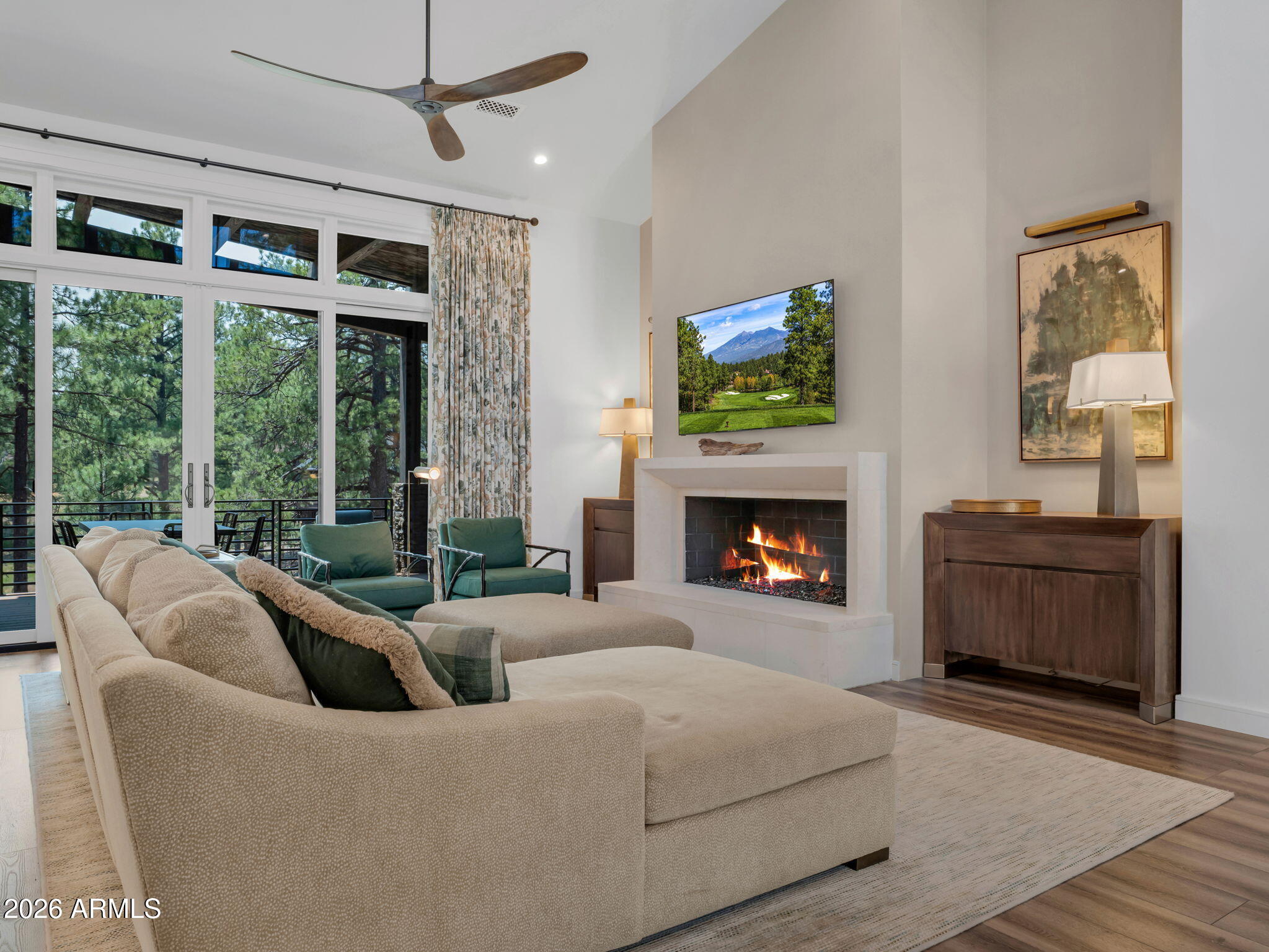 Nestled within the desirable Coconino Ridge neighborhood of Pine Canyon, this beautifully appointed 3,535-square-foot single-family home offers a refined mountain retreat surrounded by towering Ponderosa pines and views toward the Flagstaff Urban Trails System. Thoughtfully designed across two levels, the residence features four bedrooms and four-and-a-half bathrooms, blending sophisticated finishes with a bright, inviting atmosphere. The main level is anchored by a spacious great room with soaring ceilings, expansive windows, and a sleek fireplace, creating a seamless connection to the surrounding forest landscape. The open-concept kitchen is equally impressive, showcasing crisp white cabinetry, an oversized waterfall-edge island, Wolf and Sub-Zero appliances, and generous storage. An adjacent dining area and direct access to the covered deck make the home ideal for both everyday living and entertaining.
The expansive outdoor living space extends the experience into the pines, offering room for dining, relaxing, and enjoying the peaceful setting overlooking the trail corridor. The main-level primary suite serves as a private retreat, complete with serene forest views, a spa-inspired bathroom, and a custom walk-in closet. A second bedroom on the main level provides added flexibility for family or guests.
Downstairs, a generous secondary living area with custom built-ins creates the perfect space for movie nights, games, or gathering with friends and family. Two additional ensuite bedrooms offer comfortable accommodations and privacy. Completing the home is a two-car garage with epoxy flooring and extensive custom cabinetry, providing exceptional storage for every season of mountain living.
With its spacious layout, polished interiors, expansive covered deck, and tranquil views of the FUTS trail system, this Coconino Ridge residence captures an effortless balance of luxury, comfort, and connection to the outdoors.