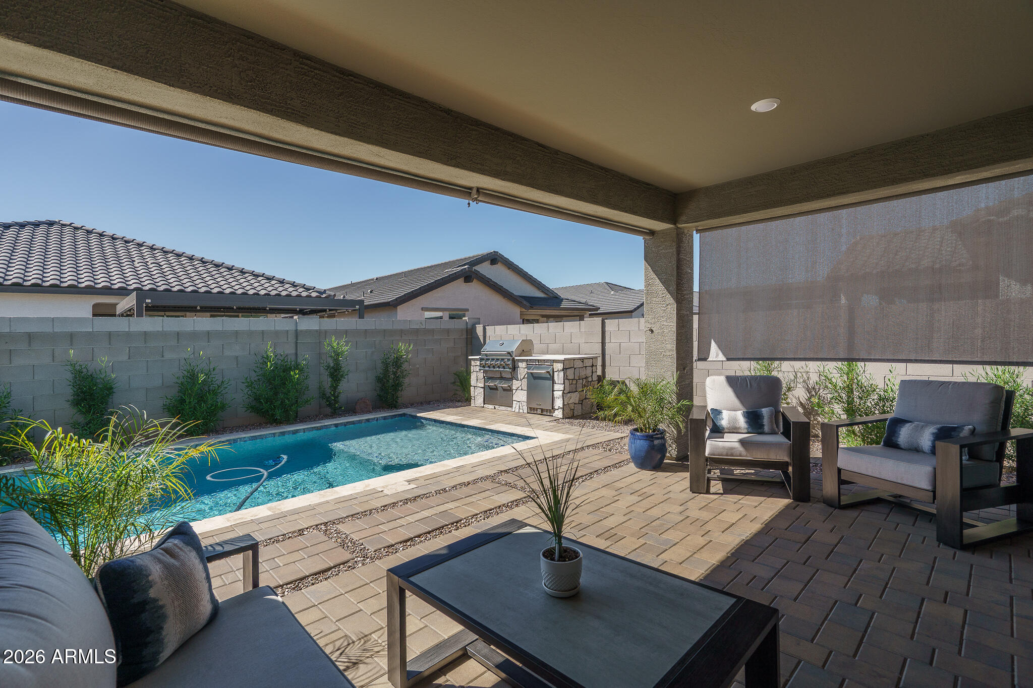 This highly upgraded loft-style home is nestled within a vibrant new master-planned community near Loop 101 and I-10, where resort-style amenities for the entire family include an aquatic center, multiple playgrounds, pickleball and sport courts, and beautifully designed outdoor spaces. Offering 4 bedrooms plus a den/office and 3.5 baths in 3076 SqFt, the open great room layout and spacious upstairs loft create an inviting environment for both relaxation and entertaining. The gourmet kitchen impresses with white cabinetry, granite countertops, tile backsplash, stainless appliances, a walk-in pantry, and a large island with breakfast bar and pendant lighting. Center-meet sliding doors lead to a stunning backyard retreat featuring a covered paver patio with roll-down shades, private pool, built-in BBQ, artificial turf, and even a custom dog house. The main-level primary suite includes a generous walk-in closet and spa-like bath with dual sinks and an oversized shower, while an additional main-level bedroom is perfect for guests. Upstairs are two secondary bedrooms and a full bath. Additional highlights include a well-appointed laundry room with cabinets, hanging rod, and sink; plank tile flooring throughout with plush carpet in the loft and bedrooms; granite counters in the baths; a drop-zone with built-in cabinetry; neutral two-tone paint; plantation shutters; designer lighting; and a 3-car garage with an EV charging station, attached cabinets and epoxy floors. This home also comes pre-wired for solar.