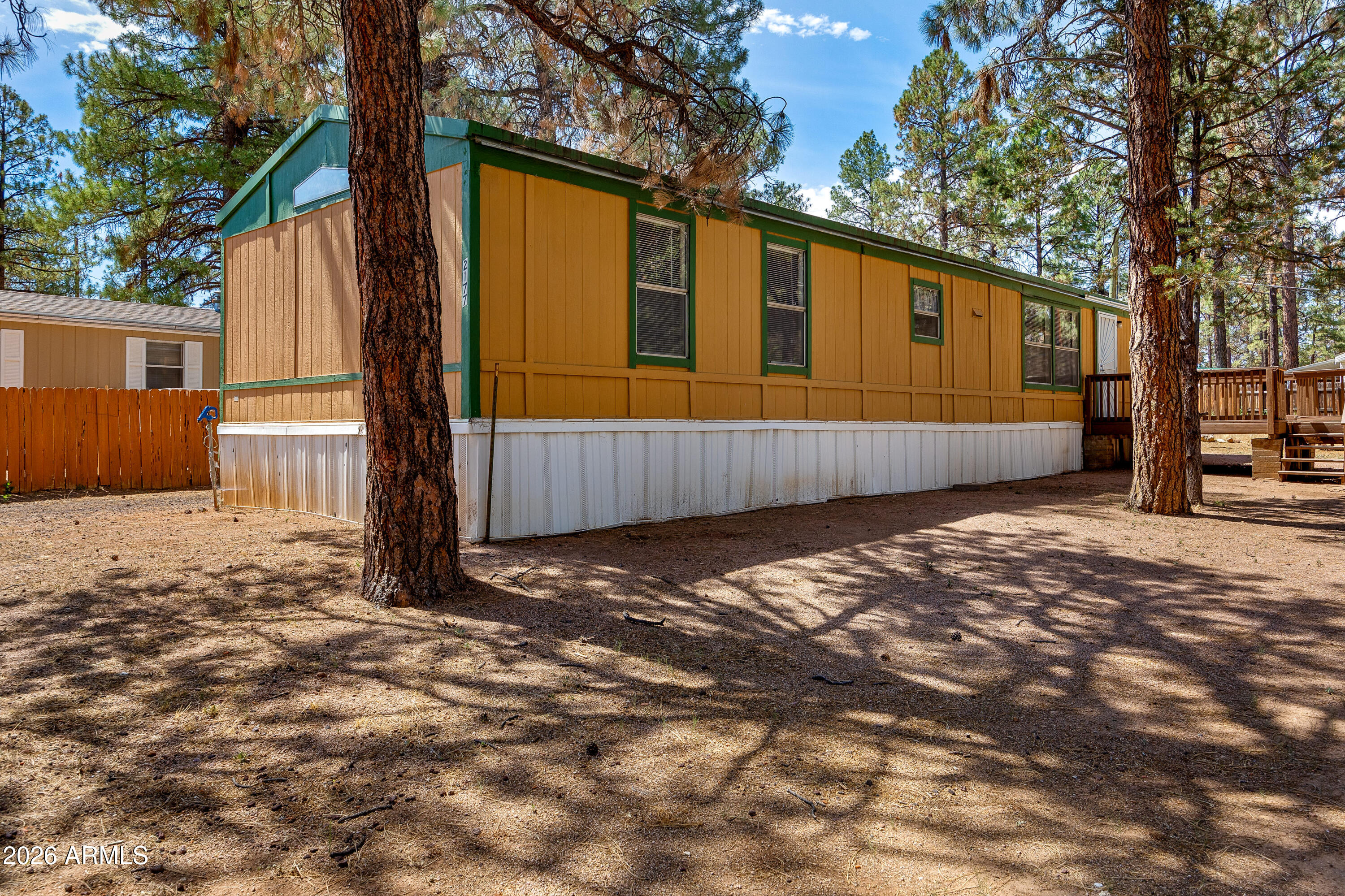 Spacious single-wide manufactured home nestled among the tall ponderosa pines in a quiet Overgaard neighborhood. At 1,120 square feet with 3 bedrooms and 2 baths, this single-level home lives large, with an open living and dining area, a vaulted ceiling, ceiling fans, and a pass-through breakfast bar connecting to the kitchen. The kitchen offers generous cabinet space, a window over the sink framing the pines, and included range, dishwasher, and refrigerator.
Clean and move-in ready, the home is comfortable as-is while leaving room to add your own touches over time. Step outside to a large deck for relaxing under the trees, plus a covered entry landing. The fully fenced lot sits on a treed 0.23-acre parcel with a metal roof and fresh skirting, and the surrounding national forest puts hiking and exploring right at your doorstep. Heber-Overgaard schools, electric service, and metered water round out the essentials.
Whether you're after an affordable full-time residence, a mountain getaway, or an investment in one of Arizona's most sought-after high-country communities, this property delivers value and room to grow. Seller is a licensed real estate agent in Arizona.