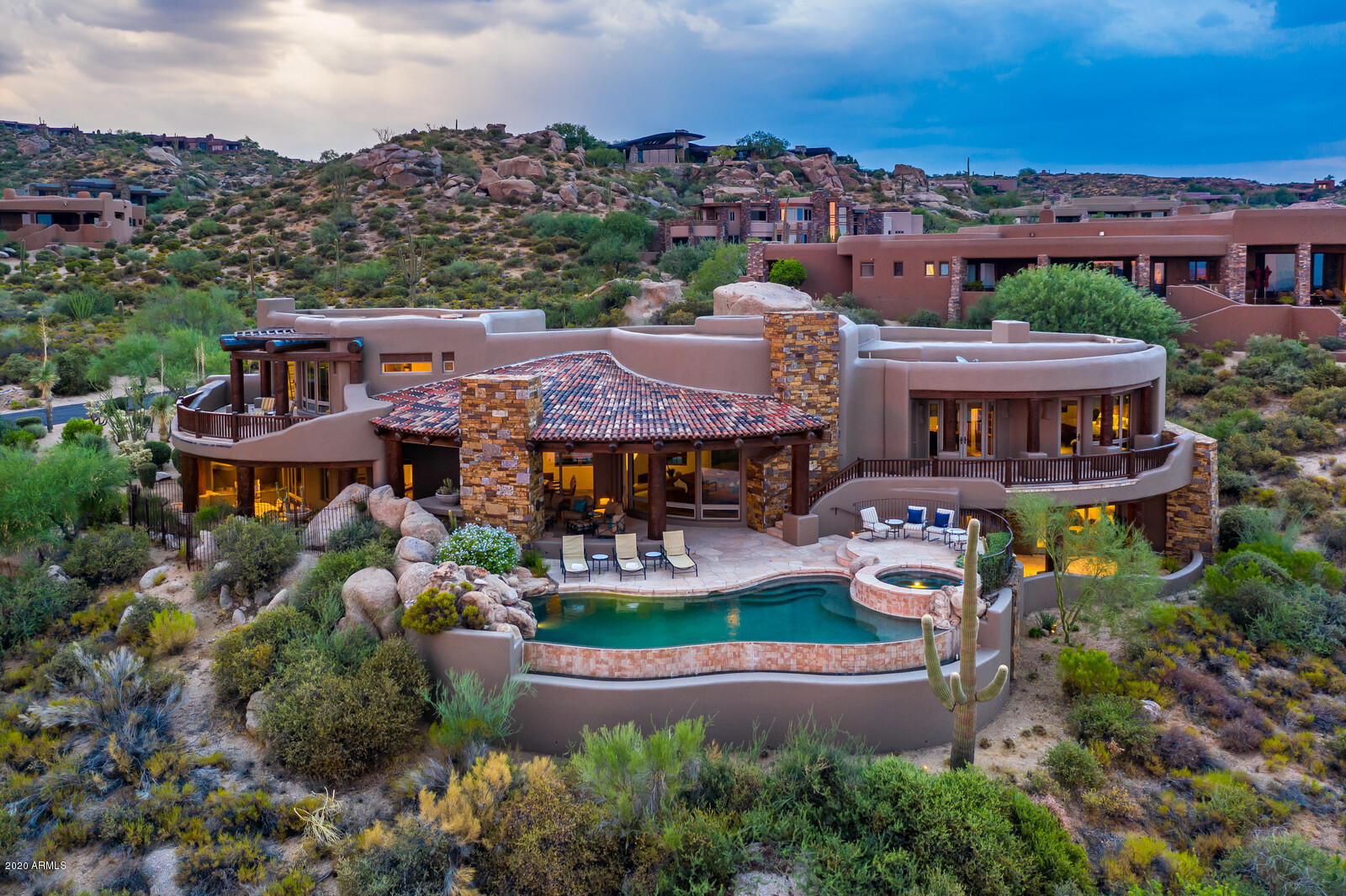 Overlooking the entire Valley of the Sun, the views from this organic southwest style home designed by Lee Hutchison are endless!  Offering spectacular city lights, gorgeous sunsets and mountain views, this light and bright home offers the finest in finishes, style and charm that Lee Hutchison is known for. From the curved walls, large lodge pole beams in the ceiling to the  cascading waterfall designed into the natural rock formation in the courtyard to the warmth and comfort of the hearth room, this home has it all. Four spacious suites, study, multiple patios, bonus room and outdoor living room complete this one of a kind home. Other features include dual dishwashers, steam shower, warming drawer and three of the four suites have access to the patio/pool/spa area.