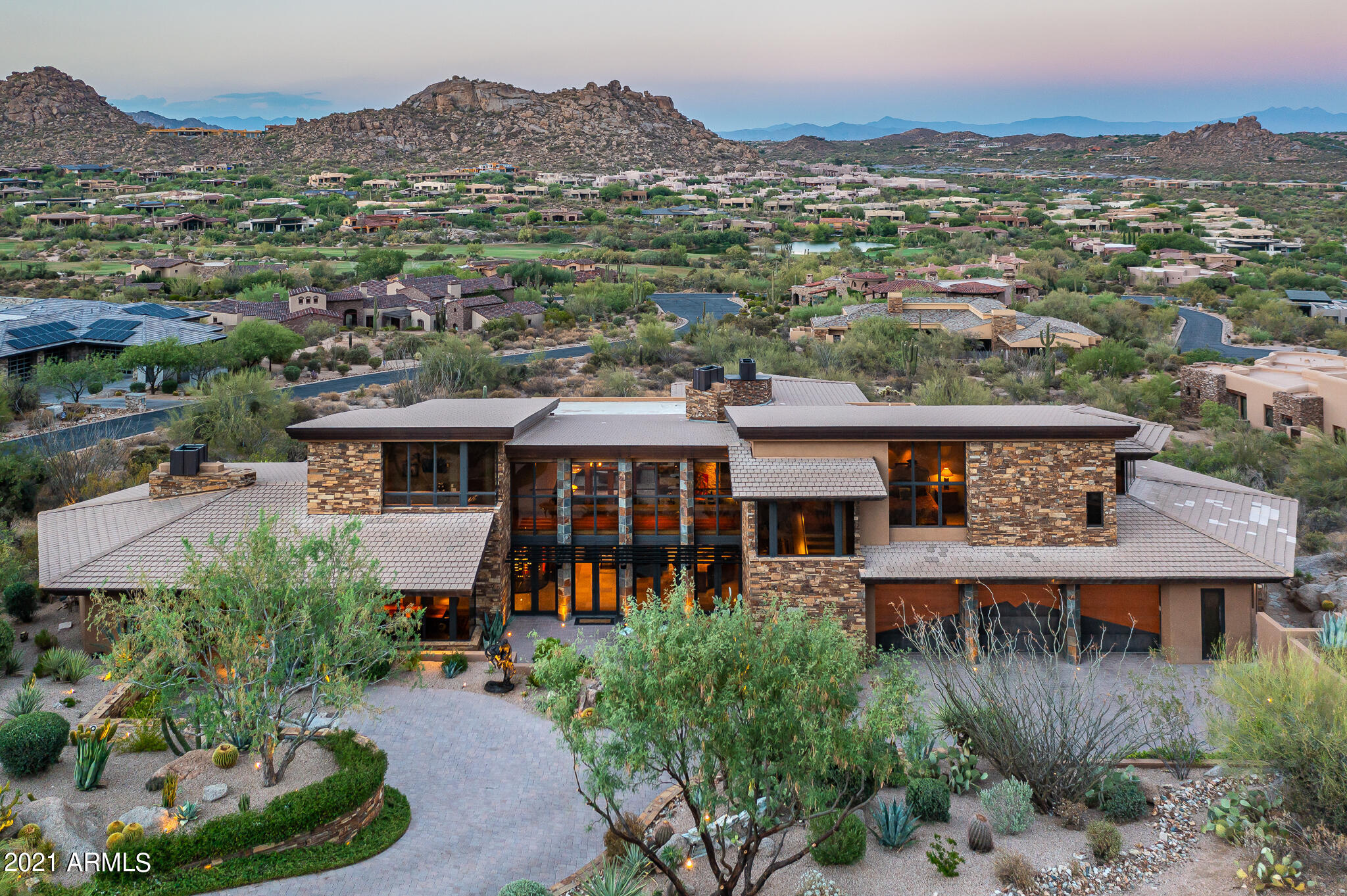 Elegant Frank Lloyd Wright inspired architecture with elevated views in the renowned community of Estancia. Timeless finishes and impeccable details are featured in this contemporary design by Mark Sever with impressive master suite and wine gallery re-created by Est Est Interiors. Materials include the use of linear metals, large glass elements, dry stack stone walls, beamed ceilings and limestone flooring. A functional and open great room floor plan with seamless indoor/outdoor living that takes advantage of the panoramic mountain and golf course views. Master suite is located on the main level with two guest suites upstairs and an attached guest house downstairs. In addition there are his/ her offices plus an exercise room. Outdoor space in the backyard includes a large covered dining patio, sundeck, outdoor kitchen, fire-pit and a heated pool/ spa with water feature. Front living space provides a cozy sitting area tucked under Pinnacle Peak and the surrounding boulders. Sited on over 1-acre of land, this home is a masterful expression of livable and functional contemporary design. Adjacent acre size lot available per separate agreement.
