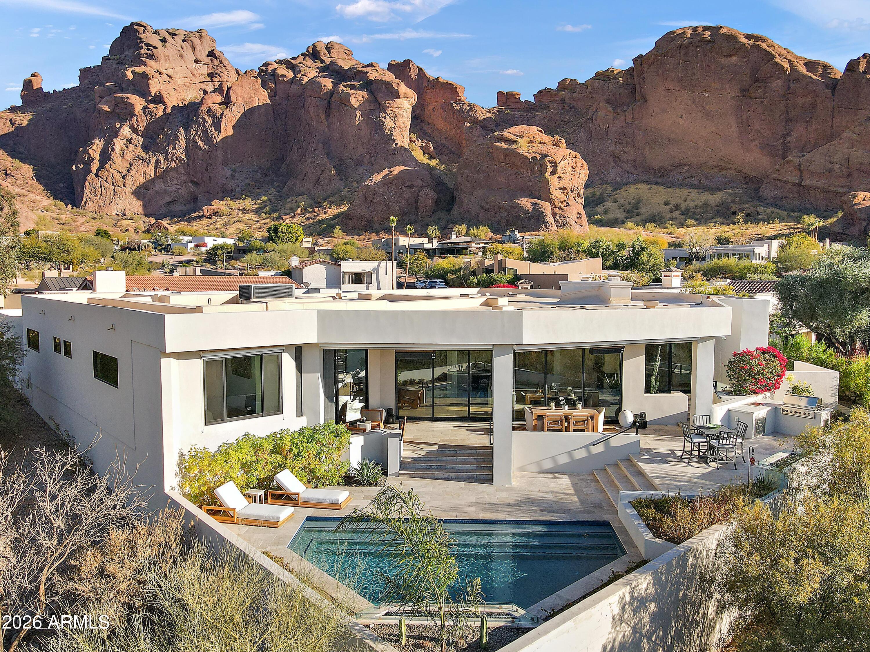 Introducing an unrivaled contemporary masterpiece by premier builder Bedbrock Development, meticulously reimagined from the ground up in 2022 with the finest luxury finishes and fixtures. This exclusive residence resides within the 24-hour guard gated enclave of Echo Canyon, perched on a truly private 10,650-sq ft lot that backs directly onto pristine Natural Area Open Space (NAOS), guaranteeing unparalleled vistas and seclusion. From every room, sweeping mountain panoramas unfold, capturing Camelback's iconic Praying Monk, the serenity of Paradise Valley, the rugged silhouette of Mummy Mountain, Carefree's Black Mountain, the striking profile of Piestewa Peak, and, on clear days, the distant White Tank Mountains.  A private oasis awaits outdoors, featuring a heated resort style pool, waterfalls, ambient lighting, and an expansive entertainment patio designed for both relaxation and lively gatherings.

5724 North Echo Canyon Drive stands alone as the sole gated home with its own private driveway, high-profile garage and storage space, dedicated guest parking for 7 vehicles, and a generous front yard, enhancing privacy while maintaining the community's elegant aesthetic. The resort style pool and shaded patio, built-in bbq and outdoor inspiration spaces against the open NAOS backdrop, deliver an elevated living experience framed by expansive mountain scenery. This distinguished sanctuary is a must see, offering an exceptional blend of luxury, privacy, and natural beauty.

Echo Canyon Private Residences comprise only 83 select lots within a professionally managed, guard gated community, offering resort style amenities such as tennis courts, illuminated nature trails, biking and walking paths.  And a soon to be extensively remodeled clubhouse, pool/spa and common area. Residents enjoy a secure, friendly and serene lifestyle of inspirational views and wonderment.