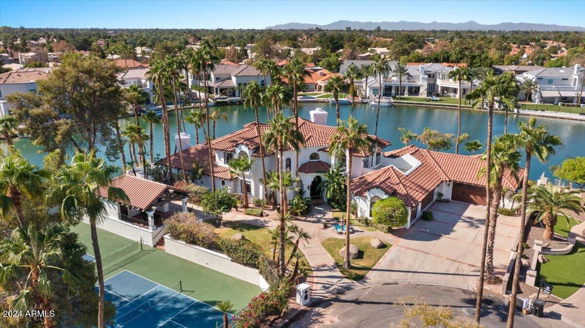Stunning Waterfront Executive beauty on huge lot built originally by Gary Geitz w/$850k recent remodel! 380' of waterfront views, negative edge pool & spa + extensive travertine decking. Incredible entertainer's kitchen, open shelving & huge quartz island that is flanked by 2 spacious living areas & onyx wet bar surrounded by windows overlooking the lake! Pet Room & 3 car garage + 2 car garage/shop w/2 double doors, 1 is open to lake. Elevator to 2nd floor bedroom, main floor primary suite w/fpl,, Main floor guest suite! W/D in every bedroom! Note the 2 pickleball courts + cabana w/bath & golf cart Gar. - could build casita next to courts! New roof 2024, New a/c's 2019. Incredible Val Vista Lakes clubhouse & amenities plus award-winning Gilbert schools & upscale dining & shopping close by