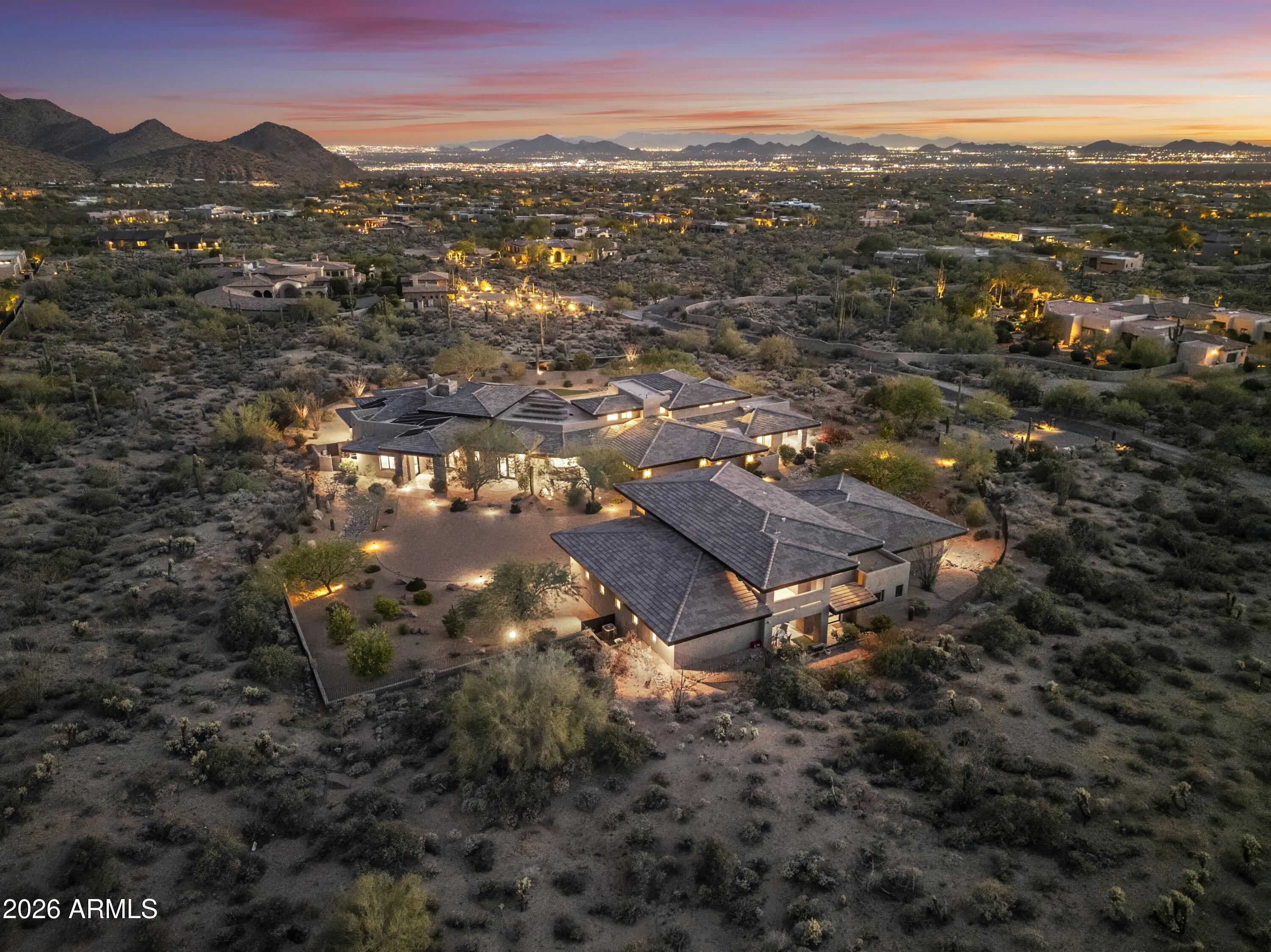 Set against a stunning 4.3-acre North Scottsdale backdrop, NO HOA masterclass desert luxury living, framed by panoramic mountain vistas and glittering city light views, for an avid collector. The 6,800-square-foot main residence is designed for both grand-scale entertaining and refined all-in-one level daily living, featuring a magnificent great room, a professional chef's kitchen with a wet bar, and a dedicated (second-level) media/billiard room. The home is thoughtfully tailored for the modern professional with dual executive offices, while the primary sanctuary offers a fireplace, coffee station, and a decadent, spa-inspired bath. The grounds are a paradise for the collector and the host alike, headlined by a massive 12-car / RV garage and GATED motor court. The outdoor oasis features oversized patios, an alfresco kitchen, a heated pool and spa positioned to capture the sunset. Completing this desert compound are TWO detached, fully equipped guest HOMES with private kitchenettes, situated across a charming front courtyard to ensure ultimate privacy for visitors. This is a rare opportunity to own a sophisticated retreat that balances immense scale with intimate, high-end detail.
