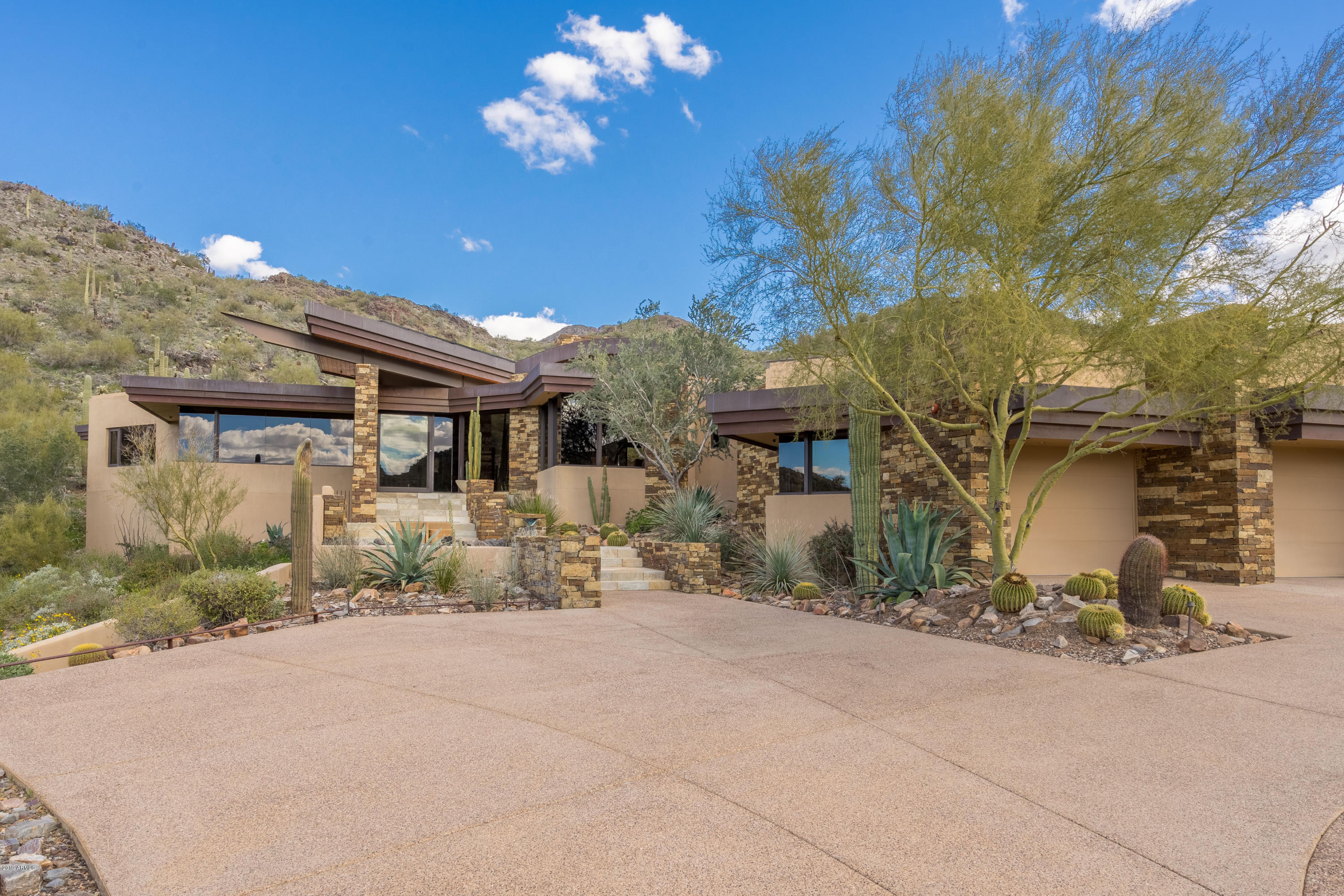 Architectural masterpiece at the top of Lost Canyon. Renowned architect, Bing Hu, has created a truly spectacular Frank Lloyd Wright inspired estate with impeccable detailing, craftsmanship, design and finishes. Sitting on over 9 acres of majestic desert landscaping, perched high onto of Lost Canyon, this incredible home boasts 4 bedrooms, including the attached guest house, a movie theater with both TV and projection, home office, workout/bonus room and 5 car garage. The great room is perfect for entertaining and features a copper detailed fireplace, full wet bar and telescoping glass doors to capture with breathtaking mountain views. The eat-in kitchen is equipped with Dacor double ovens, 6 burner gas stove, granite counter tops and back splash, Sub Zero fridge and freezer, multiple dishwashers, ample storage and oversized walk-in pantry.  The formal dining room features breathtaking views of the rolling desert hills and the twinkling lights of Scottsdale in the background.  Coming to the backyard you'll be greeted by the 40' infinity edge salt water pool, jacuzzi, outdoor kitchen, two way fireplace, huge covered patio space and a half sport court.  The home also comes with state of the art Sun Power SOLAR system to deliver low cost energy.  This sensational estate has it all, while also being incredibly private, yet conveniently located near your favorite shopping, restaurants and golf courses.