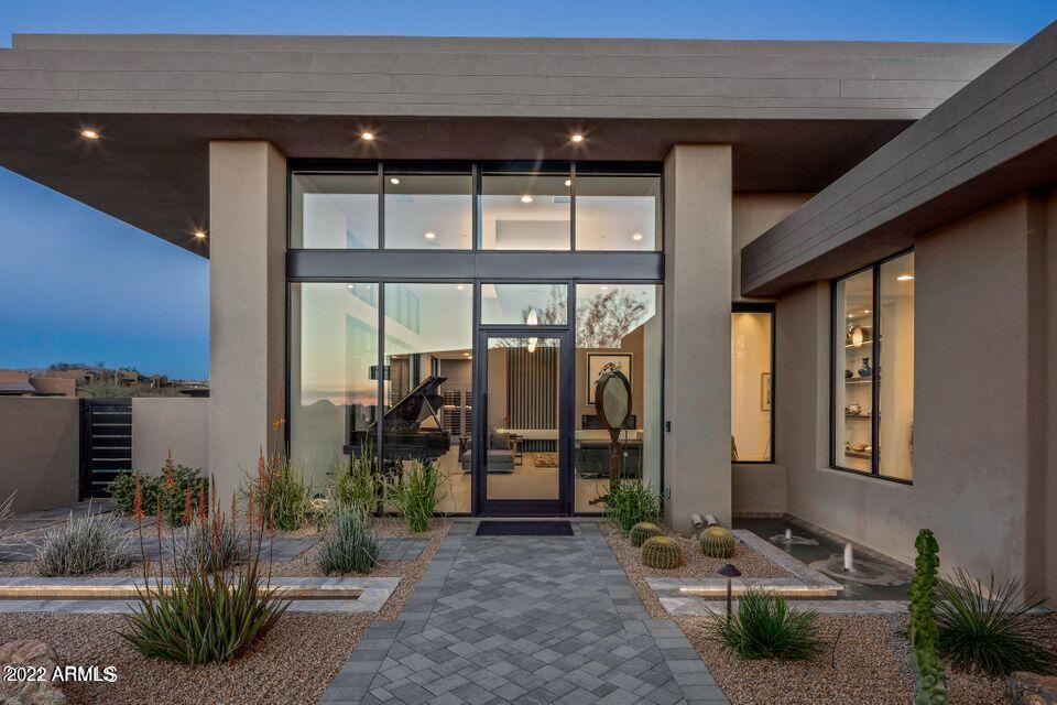 This fabulous contemporary home will take your breath away with an 16' ceiling and walls of glass. The owners have thought of everything including a separate wine bar room with passage to the patio, painted glass tile in the kitchen and quartz countertops along with an 18' stainless shelf, custom pantry with coffee bar/subzero refrigerator/freezer drawers/warming oven/ 2nd dishwasher and loads of storage, and a separate golf storage room with built-in bag and club and shoe storage. 2 guest suites are joined by a larger entertainment room with built-in storage and under-counter refrigerator. Master suite is spacious and has a coffee bar, under-counter fridge, his and her separate vanities and toilet rooms, large shower--2 separate closets and washer/dryer area.

Covered patio area and art Covered patio area and artificial turf area, poo/spa, pool bath, EVO grill and seating area with elevated gas firepit. Loads of guest parking and an oversized 3-car garage with abundant storage.