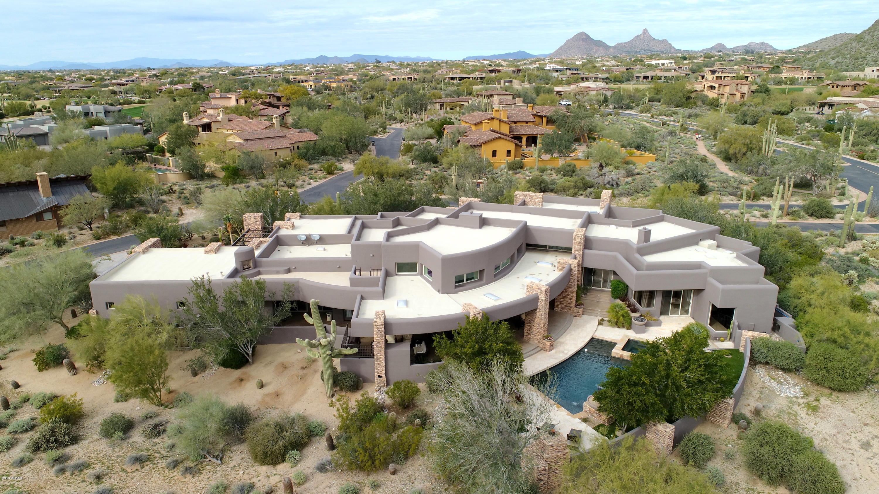 Desirable prestigious location in the heart of the DC Ranch Country Club, a few minutes walk to the club and golf course.  Boasting scenic mountain views situated on a premium acre+ corner lot, this soft contemporary custom is exceptional in every way.  A car collector's dream, with six pristine bays, built in storage, a/c, and a workshop/mudroom with full utilities/sink for convenient clean up.  Inviting guest entry with lush landscape and water feature grace the front exterior of this modern masterpiece.  Open spacious home plan perfect for formal or informal living boasts grand ceilings providing abundant natural light with large windows and skylights. Desirable split bedroom plan offers limitless living spaces with flexible design featuring a stylish horseshoe wet bar and double-sided fireplace as the heart of the living areas. Chic updated kitchen is a chef's dream with mod custom cabinetry, new Viking appliances with French style double ovens, Sub-Zero side by side, 2 dishwashers, gas cooktop with grill and griddle, and built in steamer.  Luxurious master retreat features a 3-sided fireplace that opens to bedroom, living area and master bath, a freestanding soaker tub, oversized shower, expansive split owner's closet with washer/dryer connections, and an exercise/flex room off master living area.  The master wing is complete with an executive double desk office with built-ins and a walk-in temp controlled wine room.  Ensuite secondary bedrooms each have private covered patios and an adjacent theatre room can easily be converted to a 4th bedroom with full bath access if desired.  Entertain seamlessly indoors to out, with multiple access points to resort style backyard.  Expansive covered rear patio with new bbq grill in outdoor kitchen, built in ceiling heaters, pool and spa with water features.  Meticulously maintained ideal for the discerning buyer.