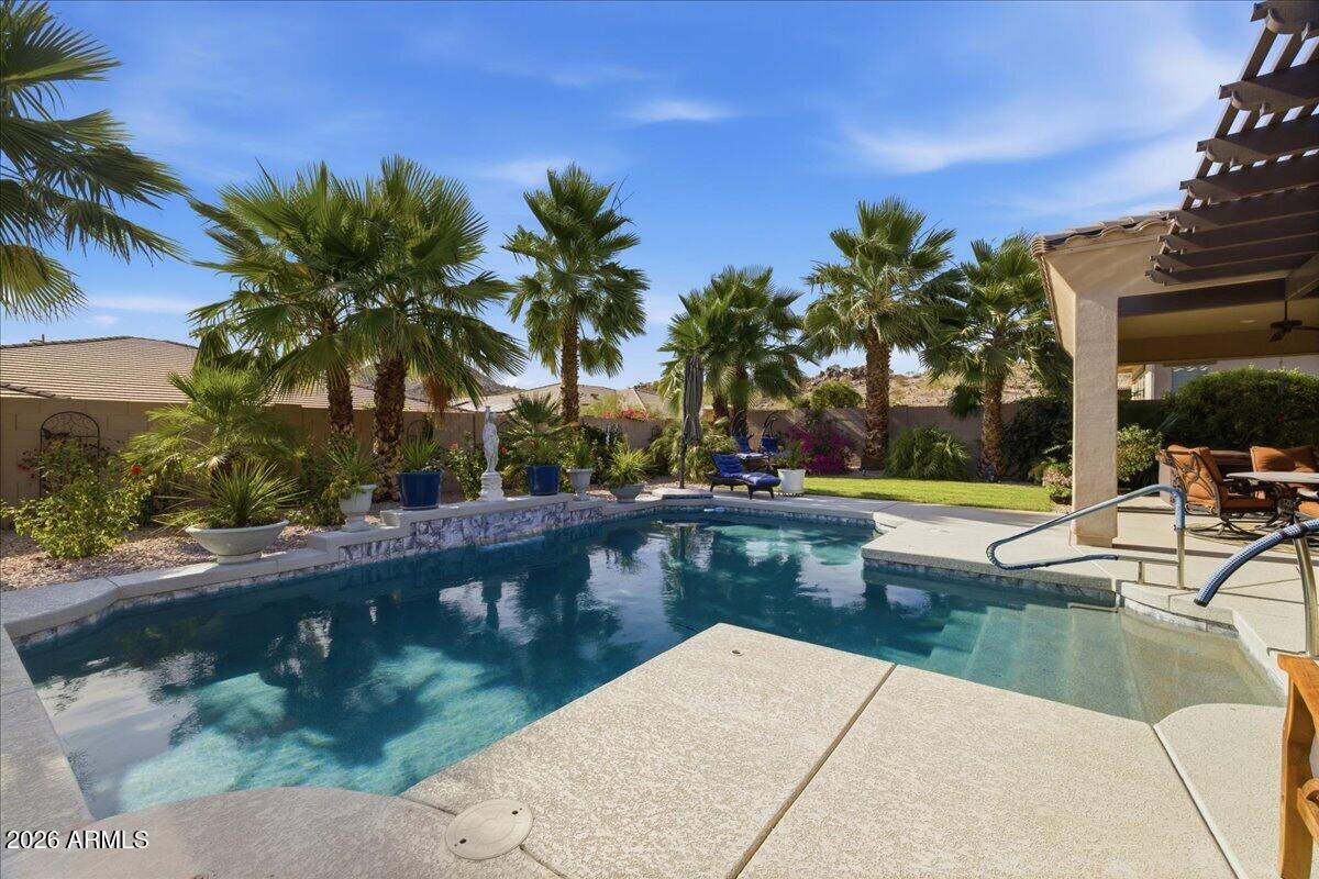 Stunning VIEWS in Gated Estrella Mountain Ranch! This refined single-level home offers open-concept living w/ premium finishes. Featuring a chef's kitchen w/ a massive island, walk-in pantry, & expansive dining, this home is built for entertaining. The split floorplan boasts a luxurious extended primary retreat with a spa-style bath and large walk-in closet, plus 2 spacious ensuite guest rooms. Large sliding doors open to a resort-style backyard with lush tropical landscaping, misters, heated pool, outdoor shower & an above-ground hot tub, the ultimate spot to watch Arizona sunsets. Includes a tandem 3-car garage and access to premier lakes, golf, and fitness centers. Paired with 72 OWNED Solar panels