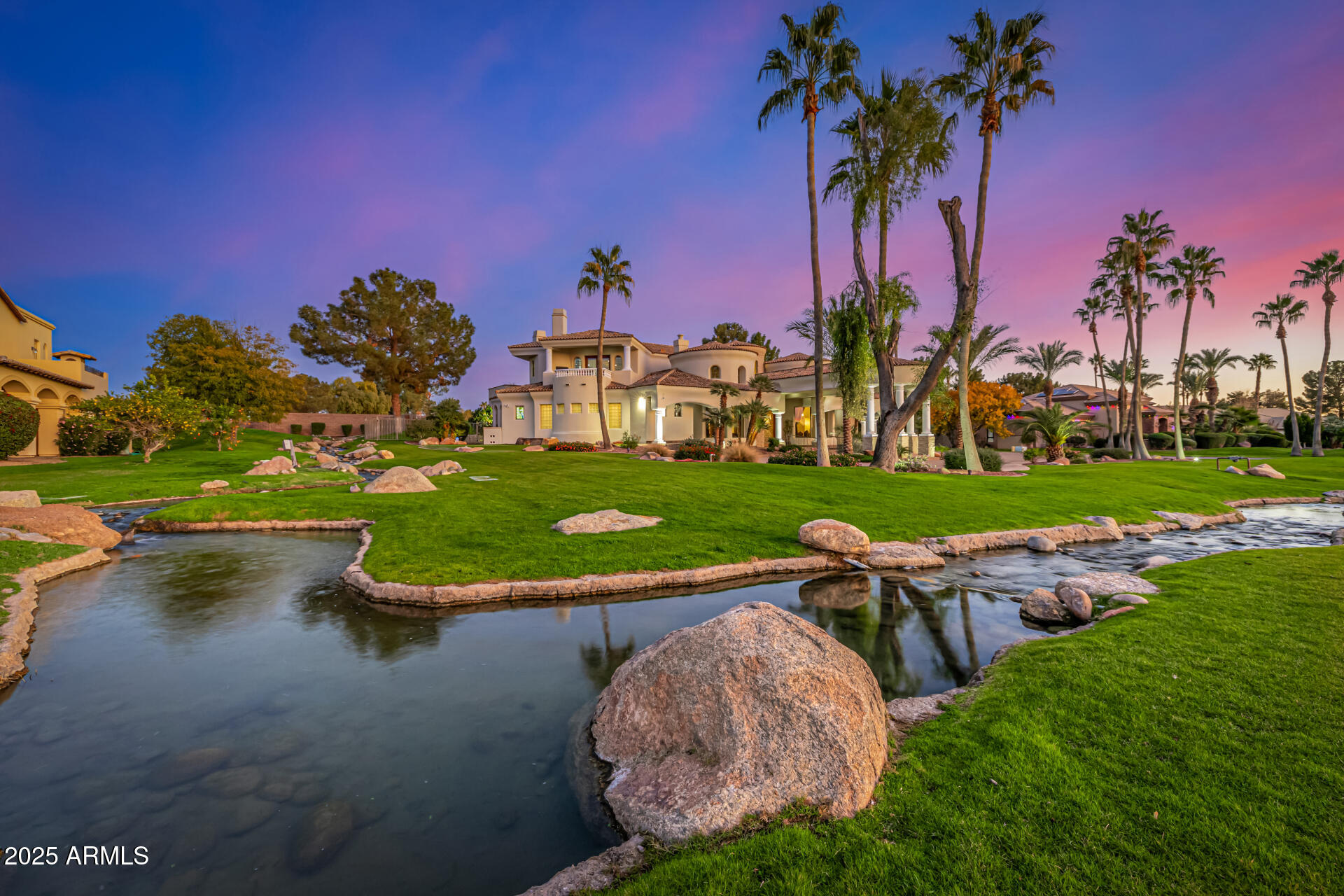 Introducing The Sunset Villa - a private retreat in Oakwood Hills. Tucked within one of Chandler's most exclusive and secluded gated enclaves, this extraordinary lakeside estate offers a level of privacy, scale, and architectural presence rarely found in the area. Set on over an acre with sweeping water and elevated patio views, this is not just a home--it's a private retreat designed for those who expect more.  Backing to a golf course, the property enjoys an added layer of privacy and open space, with elevated patios providing scenic vistas beyond the wall--creating separation without sacrificing seclusion.From the moment you arrive, the circular drive and grand portico create a sense of arrival that feels both elegant and unforgettable. Inside, a dramatic rotunda foyer opens to soaring ceilings, refined architectural details, and walls of glass that immediately draw your eye to the tranquil backyard, where water, greenery, and sky come together in perfect harmony. Designed for both grand entertaining and everyday living, the heart of the home is an expansive great room that seamlessly connects to a chef's kitchen outfitted with professional-grade appliances, oversized island seating, and thoughtfully designed gathering spaces. Whether hosting a dinner party or enjoying a quiet morning, every space feels intentional and inviting. Upstairs, a game and billiards loft with wet bar opens to The Sunset Patio--an ideal vantage point for taking in Arizona's iconic sunsets over the water. Downstairs, a true luxury amenity awaits: a fully customized theater experience that rivals commercial cinemas, complete with tiered seating, immersive sound, and rich architectural detail. The primary suite is a retreat within the home itself--featuring a private sitting room, fireplace, spa-inspired bath, and dual custom closets designed for both comfort and function. Secondary bedrooms are generously sized, each with en suite baths and positioned for privacy. Step outside and the property transforms into a resort-style sanctuary. A beach-entry pool with slide, elevated spa, multiple fireplaces, outdoor kitchen, and expansive entertaining areas are surrounded by lush landscaping, lake views, and the rare sense of space that defines Oakwood Hills. This is a neighborhood unlike anything else in Chandler--where winding water features, mature trees, and expansive green spaces create an environment that feels worlds away while remaining close to everything. South Chandler offers an exceptional quality of life, with proximity to the Price Road Corridor, top-rated Chandler Unified schools, and a vibrant lifestyle that includes year-round sunshine, parks, golf, and premier shopping and dining. For those seeking privacy, presence, and a home that stands apart--this is a rare opportunity.