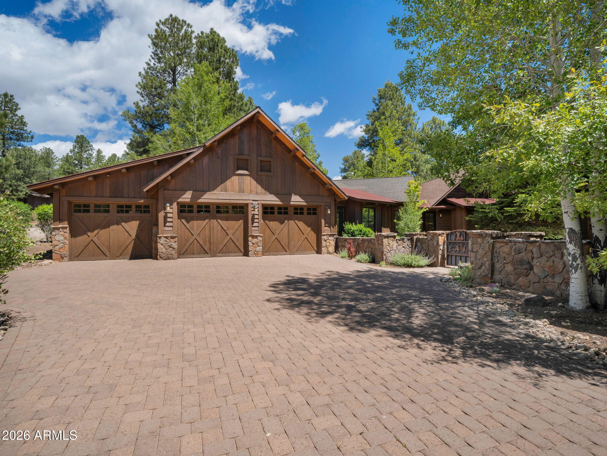 This remarkable single-level residence spans 4,315 square feet and showcases exceptional craftsmanship with custom details throughout. Enter through the private gated courtyard, framed by a spacious 3-car garage, and immediately appreciate the home's distinctive architecture highlighted by a thoughtful blend of siding materials and striking Malapai stone accents. Designed for both everyday living and entertaining, the chef's kitchen is appointed with premium stainless steel Wolf appliances, a Sub-Zero refrigerator, exquisite granite slab countertops, an oversized island with breakfast bar seating, and a temperature-controlled wine cellar, all seamlessly flowing into the Great Room. Expansive windows capture breathtaking views of the surrounding forest and golf course, creating a true connection to the natural beauty outside.
The warm mountain-inspired design is elevated by a dramatic floor-to-ceiling Malapai stone fireplace and stunning tongue-and-groove ceilings, creating an inviting cabin-style ambiance. Throughout the home, custom lighting enhances the architecture while perfectly showcasing curated art display walls and refined finishes at every turn.
