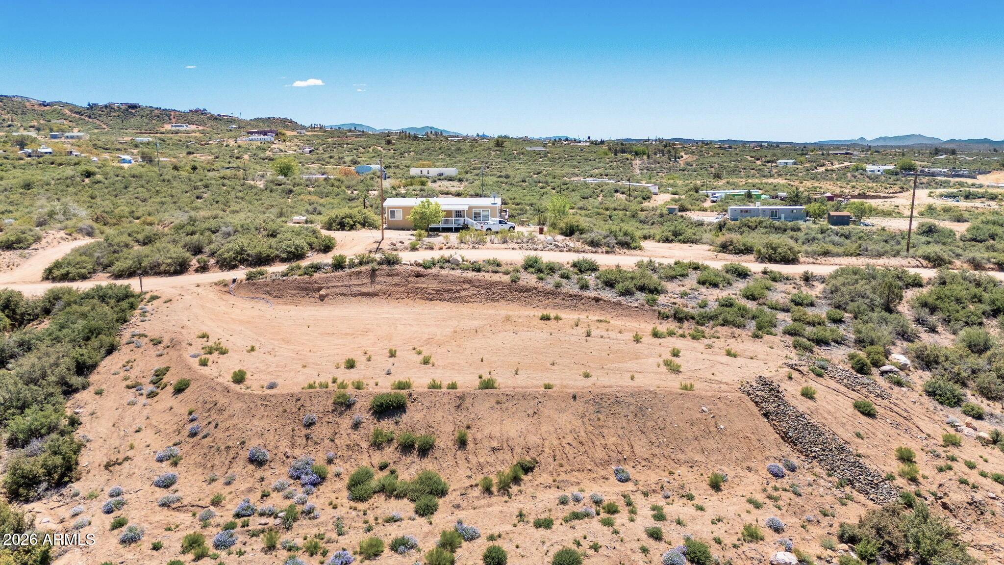 This 2+ acre lot offers the perfect setting for quiet country living, where you'll enjoy panoramic mountain views with no HOA restrictions. Improvements include septic, water meter, and a graded homesite. Electric at lot. Just one lot from the National Forest and Weaver Mountains and community is surrounded by State Trust Land and National Forest, ideal for horseback riding or hiking. Zoned for manufactured or site-built homes, horses and RVs welcome. Conveniently located about 25 minutes from Prescott's shopping, dining, schools, and medical services. County-maintained dirt road access.