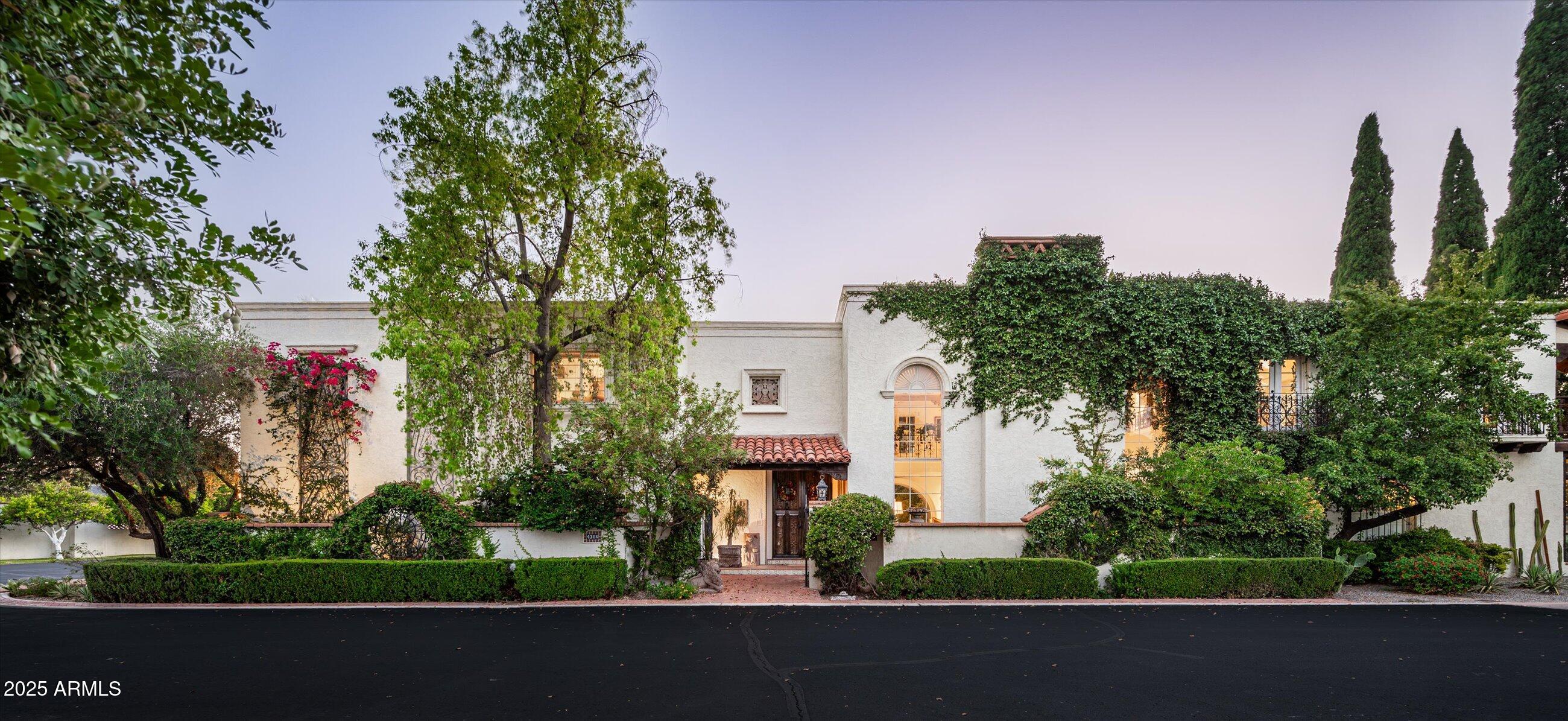 Nestled within the coveted and gated boutique enclave of Dos Puertas, this exceptional estate is a rare architectural treasure offering 6,881 square feet of refined living space on a 10,947 sqft lot. Thoughtfully designed with 4 spacious bedrooms, 4.5 luxurious bathrooms, formal and informal living spaces, galleria-style hallways, and numerous serene patios, this is a residence that transcends the ordinary.
From the moment you step through the hand-carved double doors, you're transported to a Mediterranean villa rich in detail and soul. A sweeping curved staircase with Mexican tiled risers and ornate iron railing sets the tone for the artistry found throughout. Arched picture windows, plaster walls, and gleaming Saltillo tile flooring invite you into the and gleaming Saltillo tile flooring invite you into heart of the home - each detail handcrafted and steeped in character.
The grand salon stuns with soaring 20-foot ceilings, leaded glass windows framing lush gardens and a peek of Camelback Mountain, Cantera stone fireplace, wooden corbels and beams, and intricate carved plasterwork, making it the ultimate space for elegant entertaining.
The primary suite, privately tucked on the main level behind hand-carved doors, is a sanctuary all its own. Moroccan-inspired screens, Portuguese and Mexican tiles, a cozy sunroom, and a charming corner fireplace create a rich tapestry of texture and warmth. The ensuite bath is a spa-like retreat with dual walk-in closets, a mosaic-tiled walk-in shower, sunken tub, Peacock blue cabinetry, and walls of glass that blur the lines between indoors and out.
Upstairs, three additional bedrooms -each with en-suite bathrooms and generous closet space- provide privacy and comfort for family or guests. One bedroom is currently styled as a home office, offering flexibility to fit your lifestyle. A cozy family room invites relaxed gatherings, while a stunning interior galleria overlooks the formal living room below, creating architectural drama and visual connection between the levels. Step onto the expansive second-floor balcony to take in picturesque views of the private mosaic-tiled pool and lush landscaping below- an ideal spot for morning coffee or an evening glass of wine.
The eat-in kitchen retains its authentic charm with hand-carved cabinetry adorned in doves and floral motifs, Talavera tile countertops and backsplash, a butcher block island, copper hood, and large bay window overlooking the kitchen garden. The adjacent formal dining room is a visual delight- stained glass, a built-in banquette, and hand-carved corbels and beams offer a warm and intimate setting, all with views of the dazzling blue pool.
Step outside to discover a private resort-like oasis with multiple patios, mature landscaping, and a shimmering spa, all wrapped in peaceful privacy and timeless design.
Storage abounds with a 900 sqft, air conditioned basement with exterior access.  The home is not only stunning but functional!
Located within the gates of a 21-home community known for its rose garden, green spaces, and community pool, this home is a rare offering where old-world craftsmanship meets refined luxury in Arcadia, one of the valley's most desirable neighborhoods.