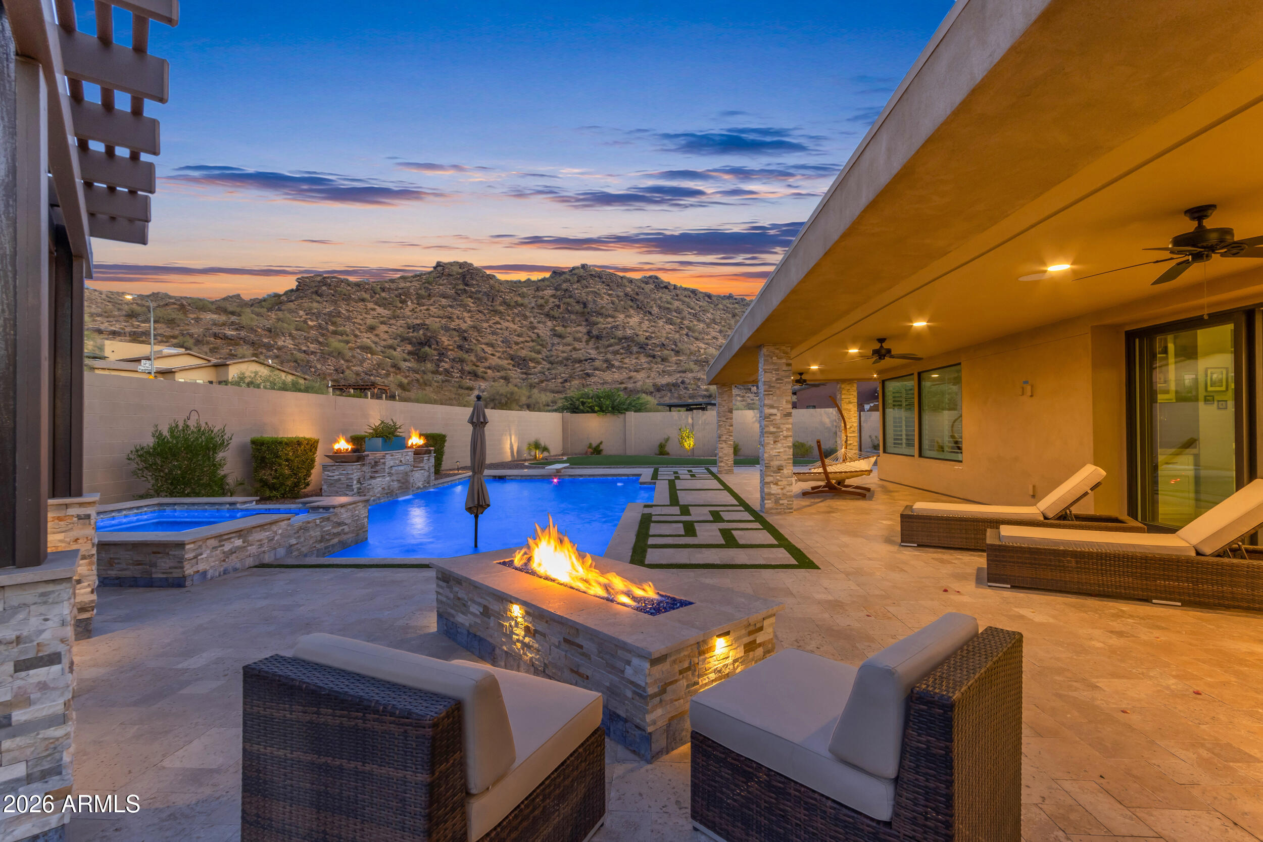 Set against the dramatic backdrop of South Mountain, this luxury executive home in a gated community delivers the kind of Arizona living buyers imagine but rarely find. Positioned on a premium oversized preserve lot, the home captures mountain views from nearly every angle while offering exceptional privacy, modern design, and a resort style backyard built for everyday enjoyment and unforgettable entertaining.

The arrival is impressive from the start, with modern desert architecture, stone accents, a paver driveway, low maintenance desert landscaping, and warm architectural lighting that makes the home glow beautifully at twilight. A private courtyard entry creates an elevated first impression with outdoor seating, pavers, a stone fireplace, outdoor TV, and a polished lounge style setting before you even step inside.

The interior opens into a bright, expansive great room with a dramatic sloped ceiling, clerestory windows, pre-wired surround sound, and an 18 foot multi-panel pocket sliding glass door that brings the backyard and mountain views directly into the main living space. The open layout connects the living room, dining area, and kitchen with a natural flow designed for both refined entertaining and comfortable everyday living. A separate game room or flex space adds even more versatility and features its own sliding glass door to the courtyard, creating another seamless indoor outdoor connection.

The kitchen is the heart of the home, designed with the scale and finish expected in an executive property. Features include quartzite countertops, an oversized island with seating, designer pendant lighting, generous cabinetry, a walk-in pantry, double ovens, upgraded appliances, a pot filler, stainless hood, and a striking blue accent tile detail at the range wall. A butler style prep area with extended cabinetry, beverage storage, glass uppers, and additional counter space adds both function and style.

The primary suite is spacious and peaceful with plantation shutters, room for a sitting area, backyard views, and a French door leading directly outside. The primary bathroom feels like a private spa with split dual vanities, upgraded lighting, a freestanding soaking tub, a large walk in shower with upgraded tile, mountain views, and an added interior door for extra privacy. The walk-in closet offers custom built-ins, drawers, hanging space, and natural light.

The split floor plan gives the home excellent privacy and flexibility. One side of the home features the spacious primary suite along with a guest ensuite, creating an ideal setup for visitors, multigenerational living, or anyone who needs a more private bedroom arrangement. The opposite wing includes two additional bedrooms, a full hall bathroom, and a separate living space that can function beautifully as a game room, teen room, media area, or flexible retreat. The secondary bedrooms feature plantation shutters, ceiling fans, neutral finishes, and bright natural light, with select rooms capturing mountain views. 

The back yard is the showpiece. Designed as a private desert resort, it features an 8-foot diving pool, heated pool and spa, extended covered patio, professional artificial turf, a three-hole putting green, outdoor kitchen with built-in BBQ, pergola dining and lounge areas, fire feature, outdoor shower, and multiple gathering spaces surrounded by South Mountain scenery. Whether relaxing under the covered patio, hosting at sunset, enjoying the spa at night, grilling by the pergola, or practicing on the putting green, this outdoor space was built to be lived in.

Additional features include a 4-car side-turn garage with insulated garage door, garage service door, RV gate, laundry room with built-in cabinetry and utility sink, built-in hallway storage, spray foam insulation, tankless water heater, and thoughtful design throughout.

Located near South Mountain Park and Preserve, this home offers immediate access to some of Phoenix's most iconic desert scenery, hiking, biking, and outdoor recreation. The setting feels peaceful and tucked away, yet the location keeps you close to shopping, dining, golf, Sky Harbor, Downtown Phoenix, Tempe, major freeway connections, and everyday conveniences. With its preserve lot, gated community setting, mountain views, split floor plan, luxury finishes, and resort style backyard, this home offers a rare combination of privacy, function, beauty, and unforgettable Arizona lifestyle.
