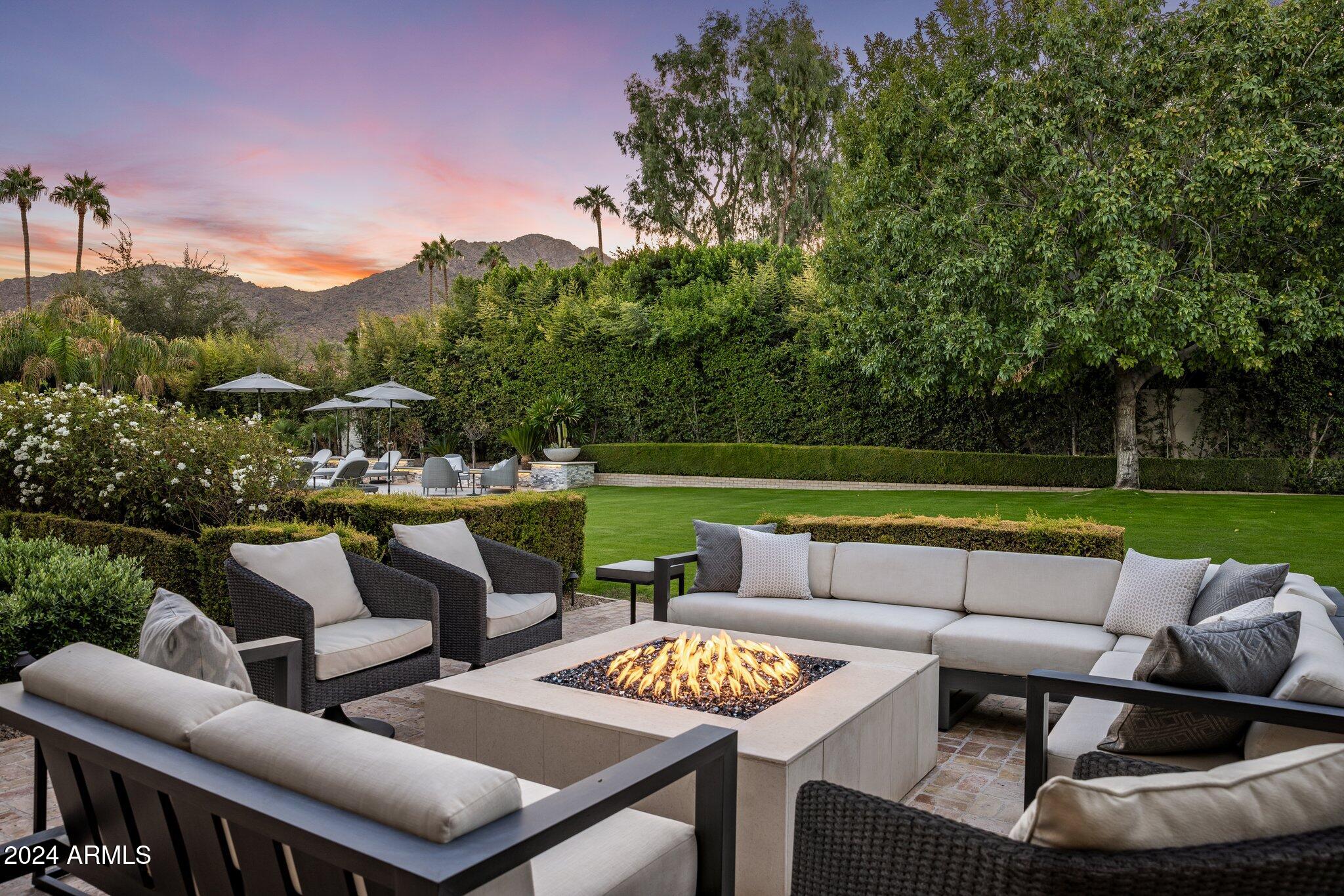 Nestled in a quiet cul-de-sac of only four homes, this charming Santa Barbara-style transitional residence offers timeless charm, tasteful updates, captivating views of Camelback Mountain and lushly landscaped grounds that are truly an oasis in the desert. The exceptional single level floorplan features 6,467 square feet in the main home with 4 ensuite bedrooms, 6 bathrooms, an office, a generous sitting room off of the primary bedroom, a fitness room, refrigerated wine room, and a 726 sq ft separate guest house. The privately gated driveway provides abundant room for parking in addition to the side-entry 4 car garage.  A paver stone walkway leads the way to the home's inviting front entrance. Inside, a striking chandelier adorns the entry foyer, which overlooks the living room with a dramatic floor-to-ceiling chevron pattern stone tile fireplace, wood plank ceiling, and views of the lush backyard.
The spacious kitchen is equipped with stainless steel appliances, stone countertops, a large center island, walk-in pantry, and a generous casual dining area. The kitchen flows into the large family room, which is perfect for both relaxing and hosting friends, with gorgeous outdoor views, a corner fireplace, a seated custom wet bar, and a refrigerated wine room with a modern mix of metal, glass and wood.
You will love unwinding in the primary bedroom wing of the home. Picture windows frame the view of Camelback Mountain in both the primary bedroom as well as the adjacent sitting room, which is well-appointed with a fireplace and wet bar. The spa-like primary bath offers marble floors, dual vanities, a makeup counter, a walk through shower, a roman tub set in front of a stacked stone fireplace, and an exterior door that opens to a private gated courtyard that encloses a built-in spa. An oversized custom closet and a fitness room complete the primary suite. Adjacent to the primary suite, an executive office with built in shelving and a wood beamed ceiling overlooks the manicured front yard and includes a wet bar, private powder room, and a large walk in closet. 
On the opposite side of the home, three spacious guest bedrooms each have their own ensuite bathrooms and walk-in closets, ensuring privacy and comfort for all.
The 726 square foot guest house, complete with a full kitchen, family room with fireplace, bedroom and bathroom, and its own covered patio, is a comfortable retreat for guests or extended family.
Outside, the backyard is an enchanted garden, with mature trees and abundant foliage set against the backdrop of Camelback Mountain. A brick walking path lined with rose bushes and lush hedges traverses the yard from one side to the other. An expansive grassy play area, approximately 90 feet long, offers endless possibilities for outdoor fun. An enormous resort-worthy pool area with multiple water features is positioned perfectly to take in the view of Camelback. A deep covered patio with Chicago brick pavers provides ample room for dining and lounging, and offers a built-in barbeque and pizza oven. Just off of the covered patio is a large gas firepit with plenty of room for guests to gather around on a cool desert evening.
This special property is conveniently located within minutes to Scottsdale Rd, Camelback Corridor, unlimited shopping and dining options, golf, and Paradise Valley's finest resorts and spas.