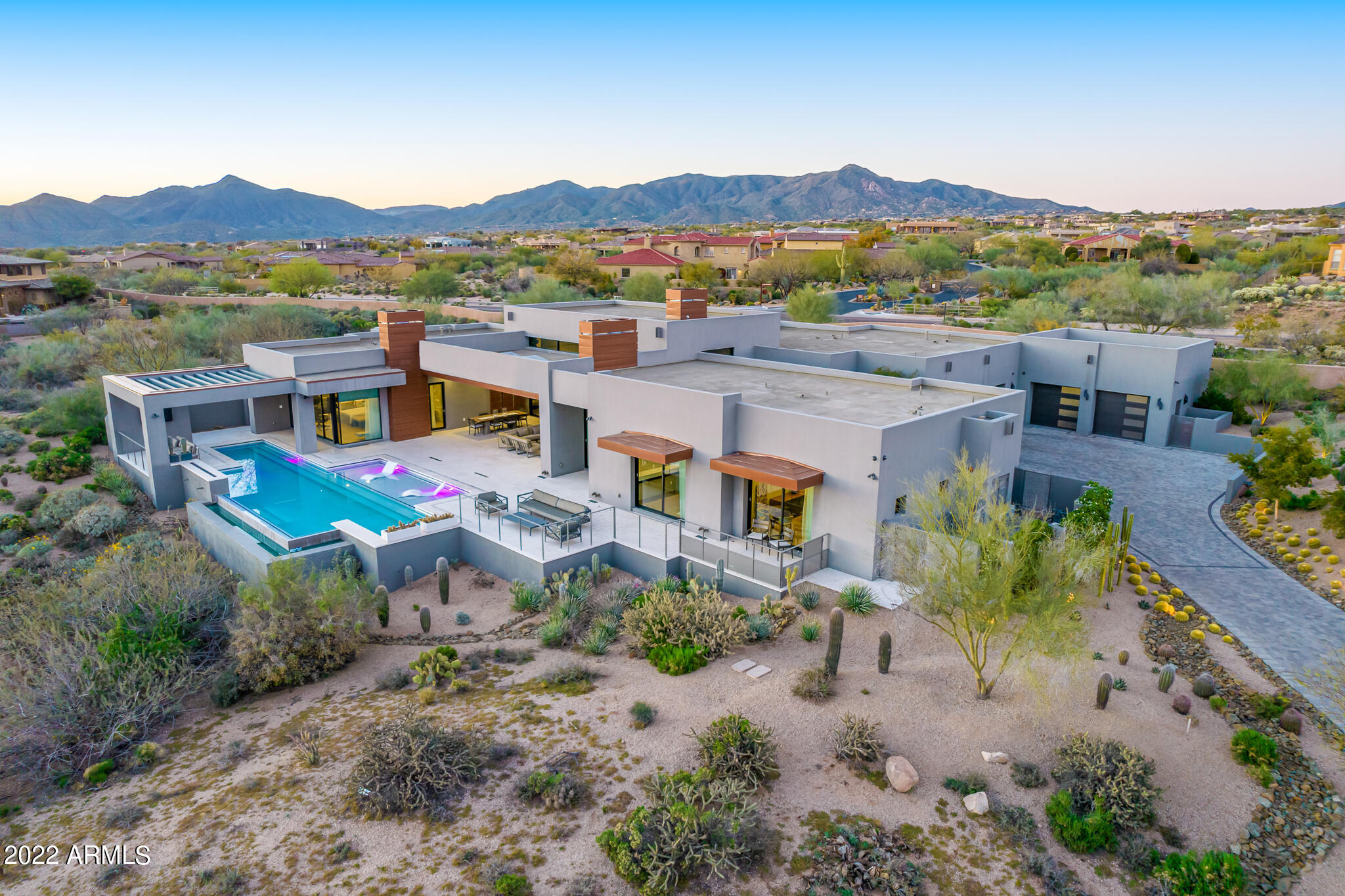 Includes TWO LOTS! This gorgeous contemporary custom home, nestled in a cul-de-sac on the northern end of the prestigious Mirabel Country Club, features many beautiful custom details, with 5 bedrooms and 5 bathrooms (including casita). Home design by Craig Wickersham Architects. Interiors,  pool, and patios designed by Beautiful Space Co.
The asymmetrical steel and glass-walled entry welcomes you into the modern, light-filled, open-plan great room, with 16ft ceilings, and 33ft multi-panel doors to one of the two spacious outdoor living room/patios.  The soaring, textured black stone, linear gas fireplace accents the spacious living room area. The adjacent entertainer's kitchen features double islands, beautiful contrasting kitchen cabinetry, 2 dishwashers, 3 Sub-Zero fridge freezer colu columns, Sub Zero wine fridge, double Wolf range, custom stone hood, and a large walk-in pantry with adjacent drop-zone.  The nearby laundry room has integrated dog kennels, and an adjacent gym/bonus room with access to the west patio.  The dining area of the great room showcases two stunning 4ft crystal chandeliers, and easy access to the west covered patio featuring a stunning 16ft cantilevered steel and stone bar with integrated Wolf barbeque, unique linear LED ceiling lighting, integrated ceiling heaters, and a high-pressure misting system.  The larger south-facing covered patio features a huge entertaining area with outdoor living and dining spaces, a linear gas fireplace/TV wall, skylights, linear LED ceiling lighting, integrated ceiling heaters, and a high-pressure misting system.  The large lap pool includes a Baja-style shelf, color changing LED accent lighting, an integrated gas fire-feature, multiple seating areas, and stunning views of the desert.  The Primary suite is entered through a beautiful Shou-Sugi-Ban wood & steel pivot door, the Primary bedroom has a unique cantilevered stone hearth, linear gas fireplace with TV, and easy access to the southern patio/pool areas through a large multi-panel sliding door.  The beautifully symmetrical Primary bathroom features a unique circular wet-dry bench, steel Japanese soaking tub located in the large wet-room shower area.  Dual vanities with abundant storage, great primary and accent lighting, and an adjacent large custom closet with integrated washer/dryer.  The north end of the home includes climate controlled, over-sized 4-car garage, and a gun room with bench and large gun safe.  The east side of the home includes a second guest suite, a large home office with built-in desks and views of the mountains, and an attached casita with separate entrance. *A Social Membership is available to transfer with purchase of the home, with Club Board approval.*