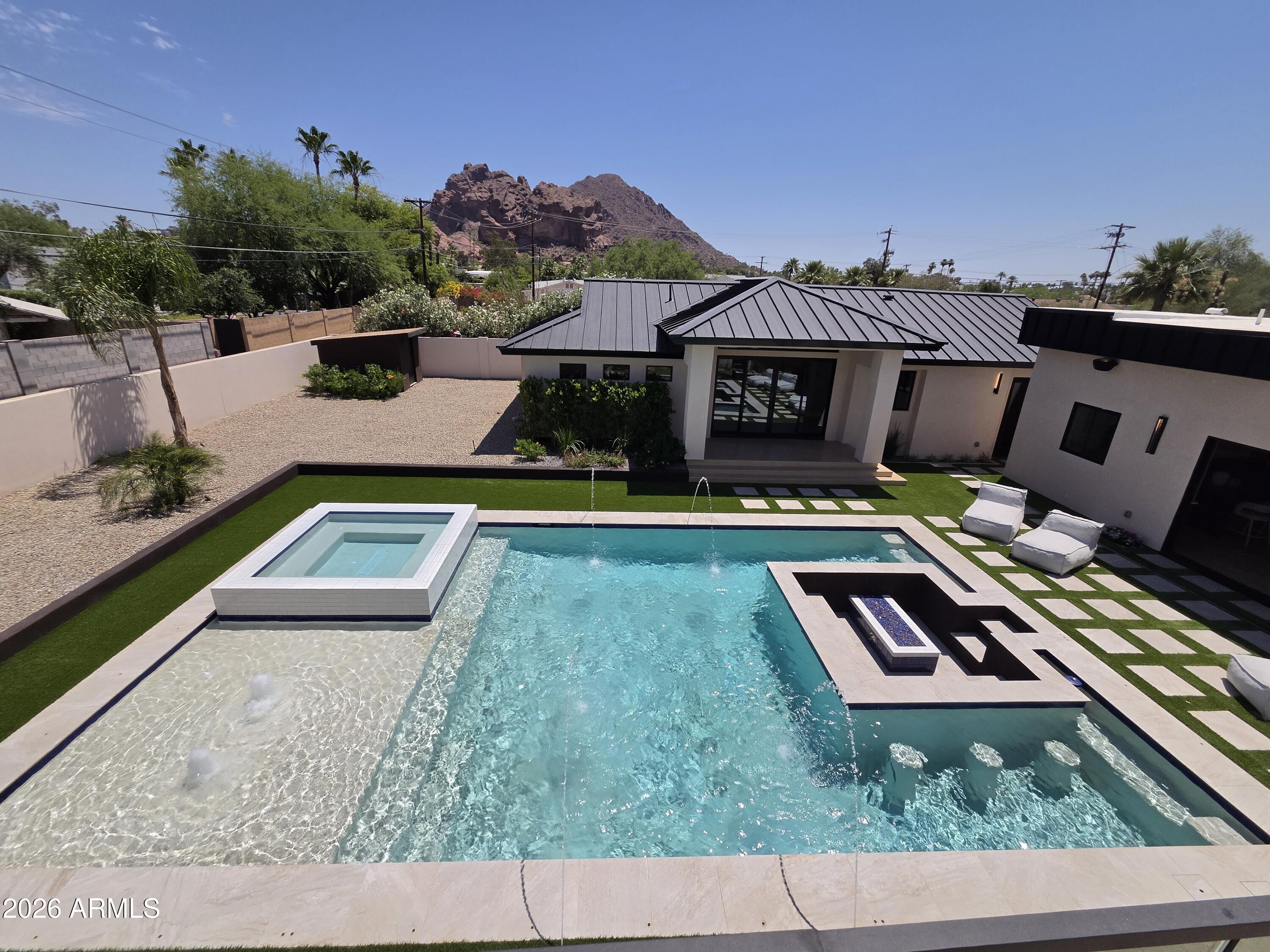 Perched perfectly to capture breathtaking views of Camelback Mountain, this new-build, modern masterpiece embodies the essence of luxury living. Illuminated oversized tile steps lead to a grand foyer that welcomes you home w/ modern sophistication. Thoughtfully designed for both grand entertainment & serene everyday living, the main residence spans over 4,000 square feet with 5 spacious bedrooms & 5 beautifully appointed baths. Every detail was curated by a professional interior designer, featuring custom cabinetry, high-end appliances, Lutron smart home system, & delicate, artful tile selections that elevate each of the 6 bathrooms & 3 kitchens throughout the property.  The home includes 3 separate laundry facilities. The heart of the home is an open-concept kitchen & great room that seamlessly connects to the outdoors, allowing for effortless indoor-outdoor entertainment. The attached guest casita suite offers a full kitchen, private entrance, & refined finishes ideal for extended family or guests seeking privacy & comfort.

A detached 1,100-square-foot pool house (or additional living suite) extends the entertainment possibilities, complete w/ a full kitchen, laundry, & an expansive upstairs living area featuring a bar, refrigerator, & full bath. Step onto the large upper balcony to entertain and take in panoramic views of Camelback Mountain; an ideal setting for sunset gatherings & quiet evenings alike.

Outdoors, the property transforms into a private resort. A stunning pool w/ a swim-up fire pit creates a dramatic centerpiece surrounded by lush yet low-maintenance landscaping, walking paths, outdoor built-in BBQ, & an inviting atmosphere for relaxation or celebration.  The air conditioned 3-car garage is wired for EV.

From the seamless flow of its multiple living spaces to the timeless, modern finishes throughout, this home exemplifies the artistry of design & the luxury of Arizona living crafted for those who appreciate beauty, comfort, & impeccable detail in every corner.