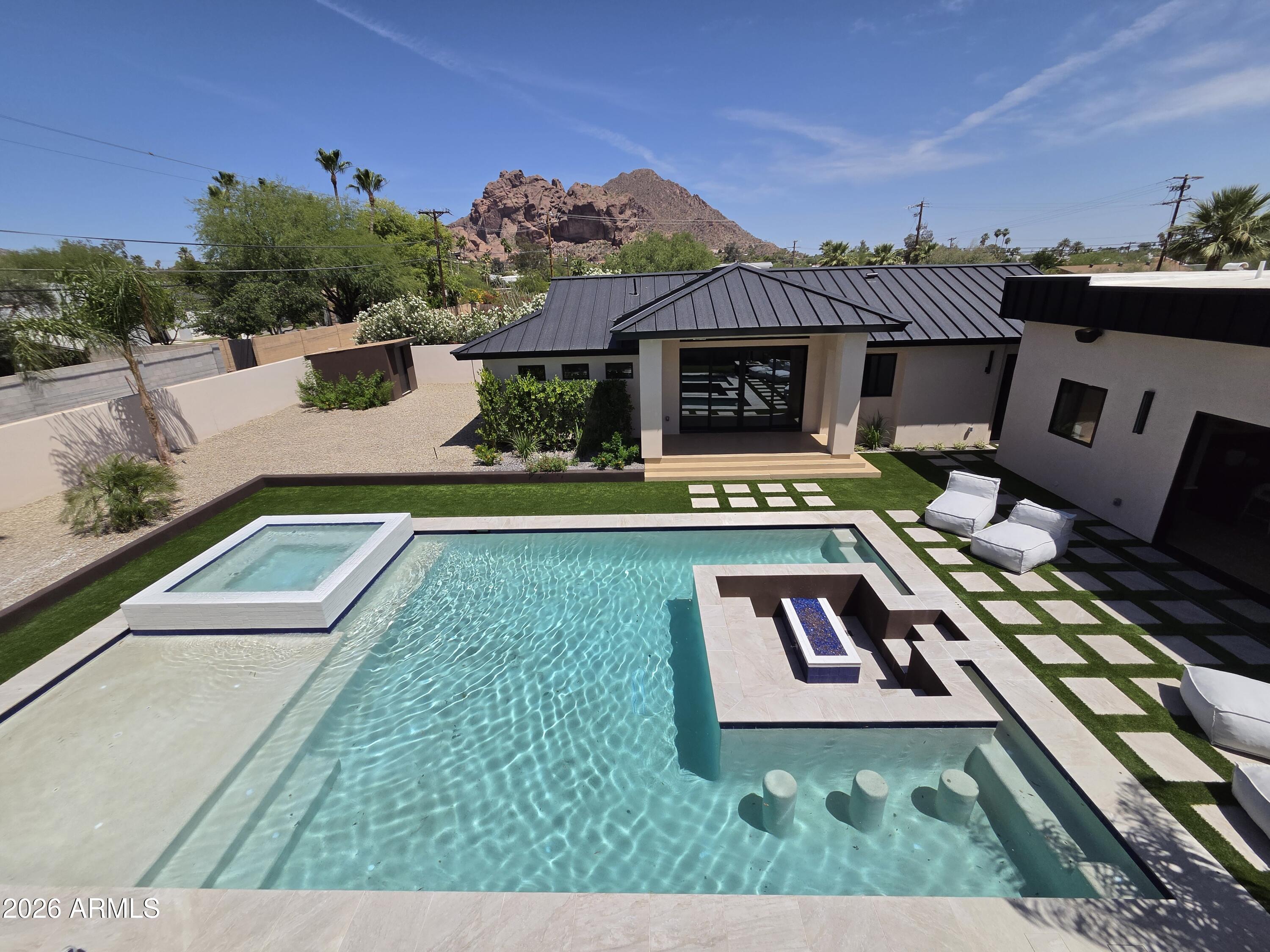 Perched perfectly to capture breathtaking views of Camelback Mountain, this new-build, modern masterpiece embodies the essence of luxury living. Illuminated oversized tile steps lead to a grand foyer that welcomes you home w/ modern sophistication. Thoughtfully designed for both grand entertainment & serene everyday living, the main residence spans over 4,000 square feet with 5 spacious bedrooms & 5 beautifully appointed baths. Every detail was curated by a professional interior designer, featuring custom cabinetry, high-end appliances, Lutron smart home system, & delicate, artful tile selections that elevate each of the 6 bathrooms & 3 kitchens throughout the property.  The home includes 3 separate laundry facilities. The heart of the home is an open-concept kitchen & great room that seamlessly connects to the outdoors, allowing for effortless indoor-outdoor entertainment. The attached guest casita suite offers a full kitchen, private entrance, & refined finishes ideal for extended family or guests seeking privacy & comfort.

A detached 1,100-square-foot pool house (or additional living suite) extends the entertainment possibilities, complete w/ a full kitchen, laundry, & an expansive upstairs living area featuring a bar, refrigerator, & full bath. Step onto the large upper balcony to entertain and take in panoramic views of Camelback Mountain; an ideal setting for sunset gatherings & quiet evenings alike.

Outdoors, the property transforms into a private resort. A stunning pool w/ a swim-up fire pit creates a dramatic centerpiece surrounded by lush yet low-maintenance landscaping, walking paths, outdoor built-in BBQ, & an inviting atmosphere for relaxation or celebration.  The air conditioned 3-car garage is wired for EV.

From the seamless flow of its multiple living spaces to the timeless, modern finishes throughout, this home exemplifies the artistry of design & the luxury of Arizona living crafted for those who appreciate beauty, comfort, & impeccable detail in every corner.