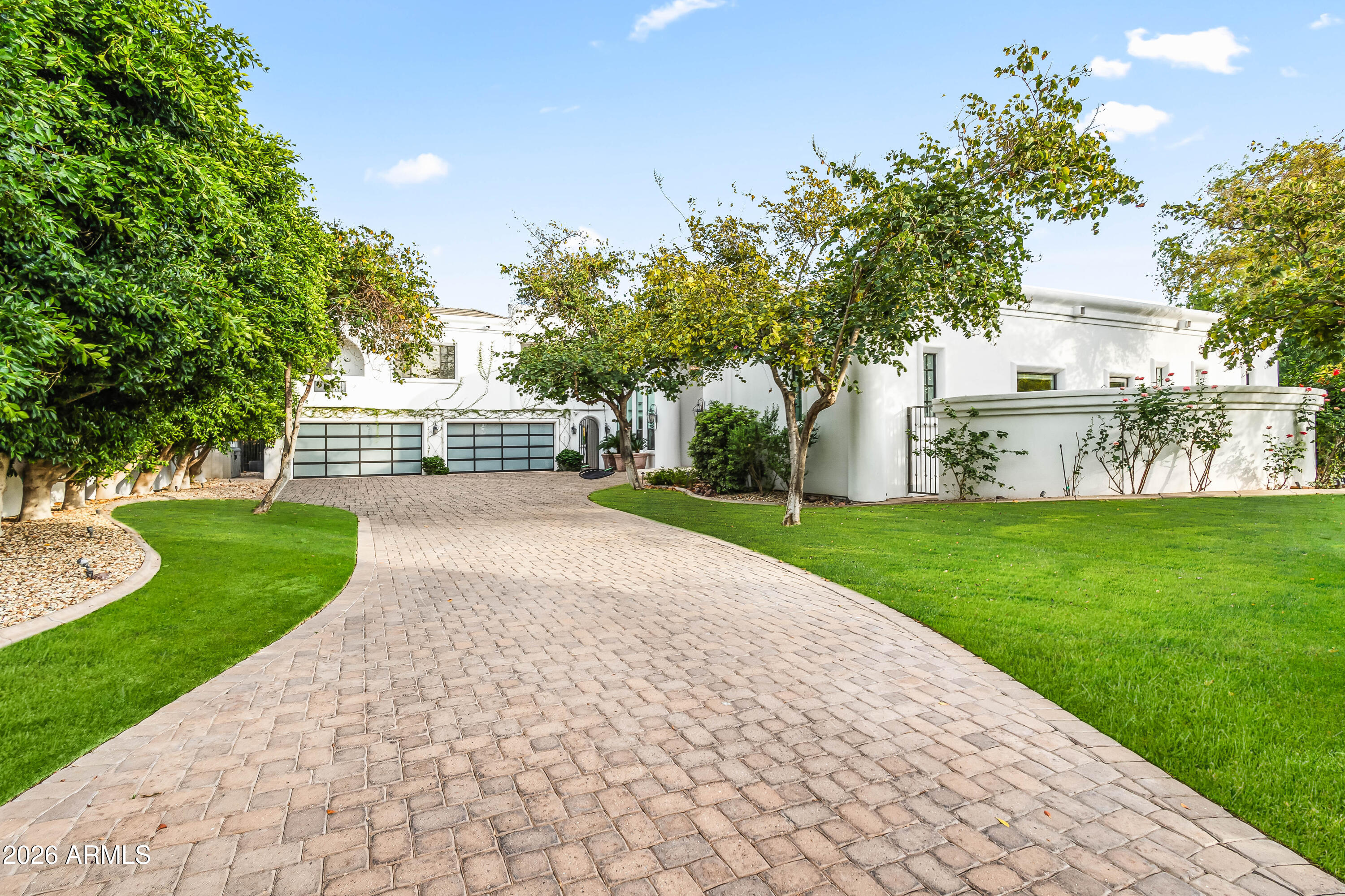 Located in the heart of Arcadia Proper with breathtaking views of Camelback Mountain, this exceptional two-story estate sits within the highly sought-after Hopi School District and features a detached guest house complete with a kitchenette--perfect for visitors or multi-generational living. Inside, the home showcases soaring ceilings, arched entryways, and white oak wood flooring throughout. The open-concept layout seamlessly connects the main living spaces, highlighted by a formal dining area with exposed wood beams and a stunning wall of windows that fills the home with natural light. The chef's kitchen is a true centerpiece, equipped with high-end appliances, custom cabinetry, a gas range, multiple ovens, two islands, and a wet bar with wine refrigerator. The adjoining family room features a gas fireplace and a wall of sliding doors that create effortless indoor-outdoor living. The primary suite offers a private retreat with paneled walls, wood-accented ceilings, its own gas fireplace, dual walk-in closets, and direct backyard access. The spa-inspired bathroom includes a jetted soaking tub, dual vanities, and a private water closet. The resort-style backyard is designed for entertaining, featuring a custom pool and spa with water feature, outdoor kitchen, and multiple covered and uncovered patio areas. Expansive grassy areas complete the outdoor space, offering both beauty and functionality. Additional features include a home theater, gym with sauna, dedicated office, and a versatile bonus room ideal for a playroom, game room, or additional workspace. A four-car garage and ample additional parking add convenience. This is a rare opportunity to own in one of Phoenix's most desirable neighborhoods, just minutes from fine dining, shopping, resorts, and golf.
