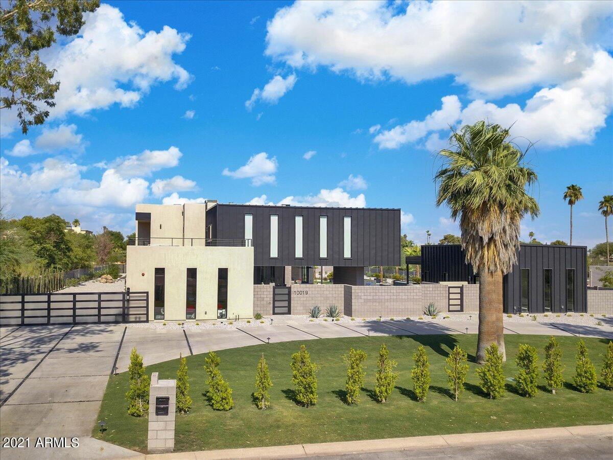 This custom-built modern house is in the highly desirable location of Paradise Valley. It epitomizes a combination of form, function, design, beauty, and utility. The contemporary home utilizes a great quantity of material with natural finishes and little to no maintenance like blocks, exposed metal beams, or glass. The residence, designed by ''Chouinard Design Studio,'' has a clever layout bringing in more shade and maximizing privacy in the right areas. An architectural ingenuity pushes the envelope and raises the bar for modern luxury in Arizona. Ambient smart controlled lighting encompasses the house to match your mood or a hosted party's theme. The uniqueness of the property is a sight one has to witness in person. The glass stairs are a spectacle in themselves as the centerpiece of this modern mansion. Lit with distinctive LED lighting capable of changing into every color on the spectrum, the staircase offers a striking display. The breathtaking master bedroom incorporates its own private patio. The high-end smart electric fireplace inside of it can be controlled by your smartphone. You will certainly appreciate the well-lit cabinet lighting and handy washer and dryer combo right in the closet. Your luxury clothes have finally found their home. The master bathroom's walls are carved out of 18 book-match quartz slabs, the veins flowing like a river from one slab to the other. The flooring is custom-cut from the same quartz slabs to match the walls. The shower, built with the latest misting technology, is meant to save water. The LED lights adorn the mirrors and cabinets' undersides, adding additional ambiance to the room.
Upstairs, there are 4 bedrooms, each with its own bathroom and closet. Each bathroom has a special pattern with waterfall counters, floating cabinets, and ambient lighting; additionally, the closets have dual texture finish panels. Every room has a private patio, granting a view of the mountains surrounding the house. Every bathroom contains a uniquely styled shower that has a waterfall shower with body jets.
The astounding gaming room is the center of attraction. It has a steel sculptural form that extends south toward Mummy Mountain, the backdrop for the ultimate play area. The wall's athletic painting patterns combined with the space for a built-in home theater and pool table are meant to bring out the gaming spirit. Enjoy the bar area's ice cooler, dishwasher, and mini-fridge capable of providing for an impressive party. Fully savor the exceptional walk-in wine cooler capable of holding 600 bottles. A huge balcony on either side with views to match the taste imply that one can't go wrong in calling this the best modern man cave of all time.
Ever have friends over and realize you need a separate and private place to stay? Well, fear no more, this home comes with a casita equipped with everything a person needs for a comfortable stay: a bathroom, bedroom, kitchen, closet, and even a laundry room. Your guests will have all the space they need with the sight of the pool/spa while enjoying the 5-star resort-like views and lifestyle.
Multiple patios are all around the home to entertain your family and take advantage of the mild winters offered. Relish the large private patio underneath the game room while soaking in the picturesque resort-style yard. The yard is hardscape with the unique concrete interlaced with artificial turf, allowing for the most useful space while enhancing the visual pedigree. There is a sizeable grassy area in the backyard; in addition, it's big enough to put in a tennis, basketball, or volleyball court. You may also keep it as grass. The yard is truly a blank canvas.
The immense resort size pool is not only loaded with smart features but also has numerous functions such as lounging or sunbathing areas, kids play areas, fountains, and waterfalls. The pool is surrounded by fire and water features and hidden laminar jets with LEDs, adding an extra dimension to the look and feel of the area especially at night. The sunken area is fantastic for gathering by the pool, having a drink, and keeping an eye on things. It has a sophisticated drainage system so that even in the worst of monsoons it won't fill with water.
The built-in grill has a feature you are not going to find anywhere else. Come and see for yourself. The light is designed to shine through the stone in key areas, allowing you to keep grilling and chilling by the pool long after the sun has gone down. The BBQ area comprises not only of a top-of-the-line Wolf BBQ grill but also a chef's dream wok cooktop. There is no video or description long enough to explain every feature that has been carefully tailored for this house with attention to detail.