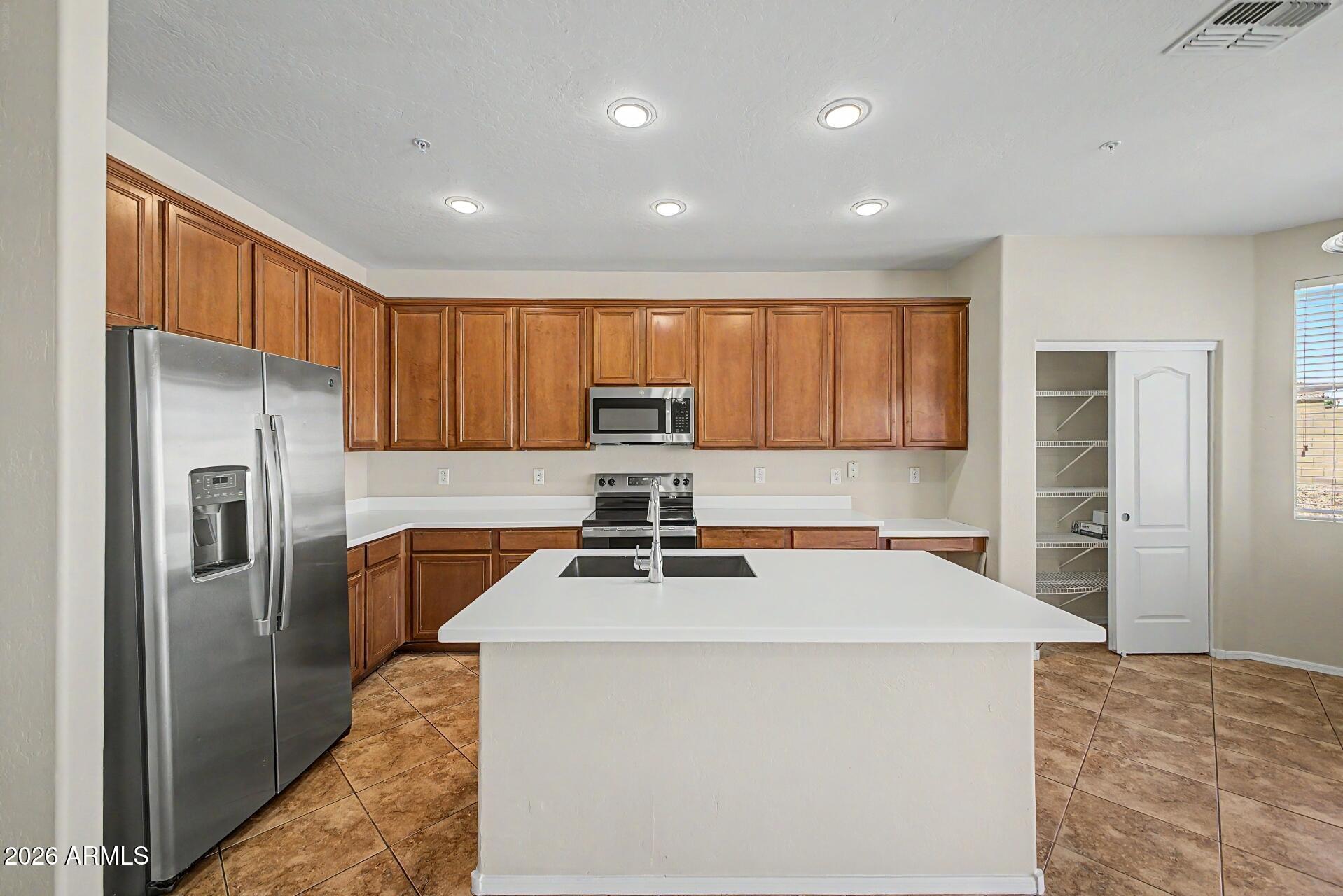 BACK ON MARKET! Giving you a rare second chance to secure this move-in-ready, single-story Laveen Ranch home. Offering nearly 2,400 square feet of highly functional living space, the sought-after ''Tessera'' split floor plan positions the private primary suite entirely away from the secondary bedrooms. A comprehensive interior refresh includes brand-new countertops, freshly painted kitchen cabinets, new carpet, neutral interior paint, and a new electric range. The spacious kitchen features a central preparation island and a walk-in pantry, opening directly into a vaulted great room designed for easy hosting. Practical storage is a standout feature, highlighted by a rare 3-car garage and a wide side RV gate with clean block fencing. The low-maintenance backyard features automated irrigation and mountain views. Located just a short walk from the community park and playground, with easy access to the Loop 202 and baseline corridor shopping.