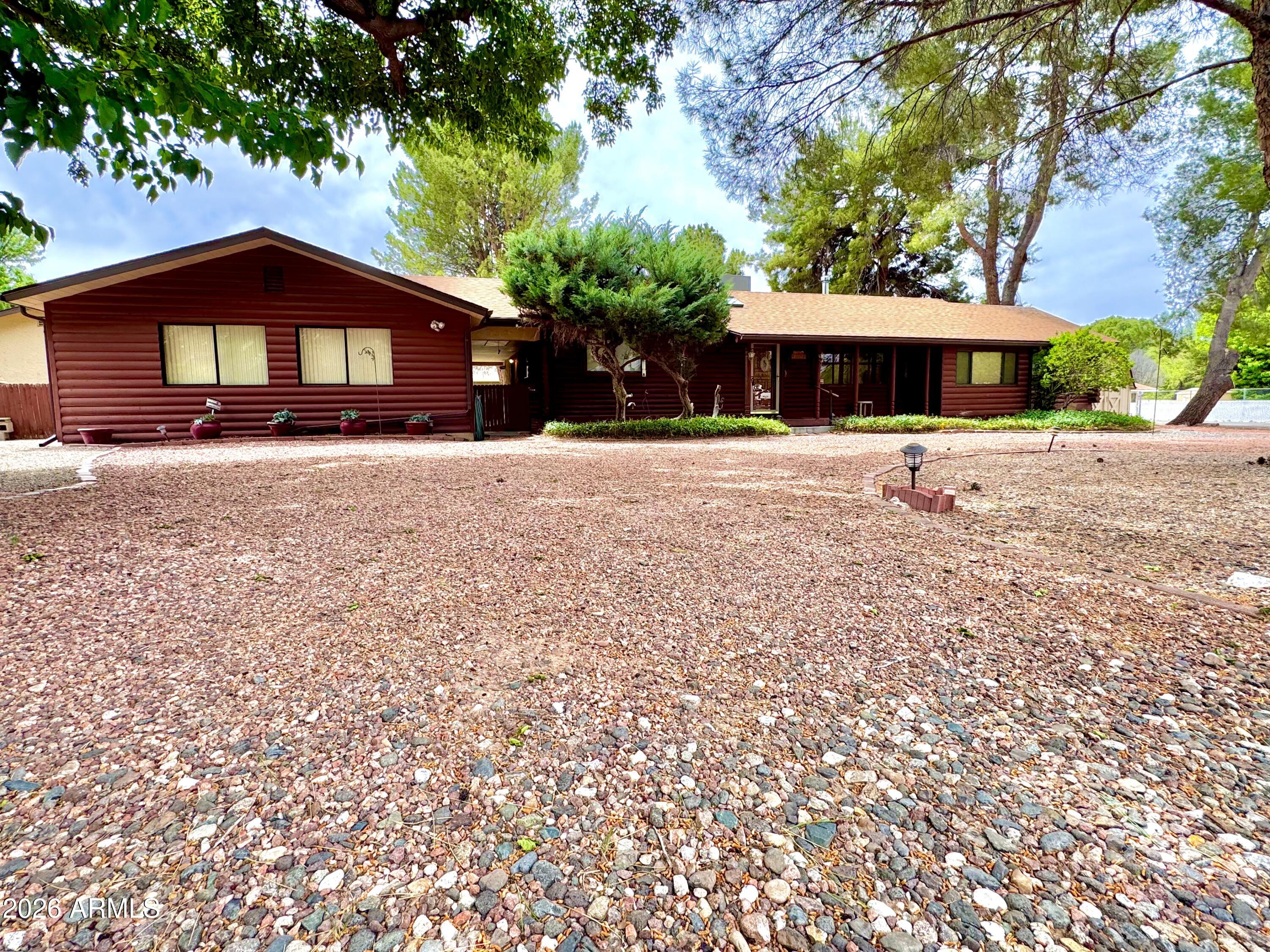 Tucked in the tree-lined greenbelt near Wet Beaver Creek, this 1-of-a-kind property blends rustic charm with exceptional functionality on nearly half an acre without the worry of being in the floodplain. The original 1965 log cabin sets the tone with warmth and character, seamlessly expanded in 1997 to create a comfortable 2 bed, 2 bath main home (1,764 sq ft). Just steps away, a guest house offers 2 potential additional bedrooms, a bathroom, and 960 sq ft perfect for extended family, guests, or income potential. Where this property truly stands apart is the massive 1,632 sq ft detached garage and shop. With space for 4 vehicles,  two extra tall bays designed to accommodate a Class A motorhome. Properties with this level of flexibility, character, and garage capacity rarely come available
